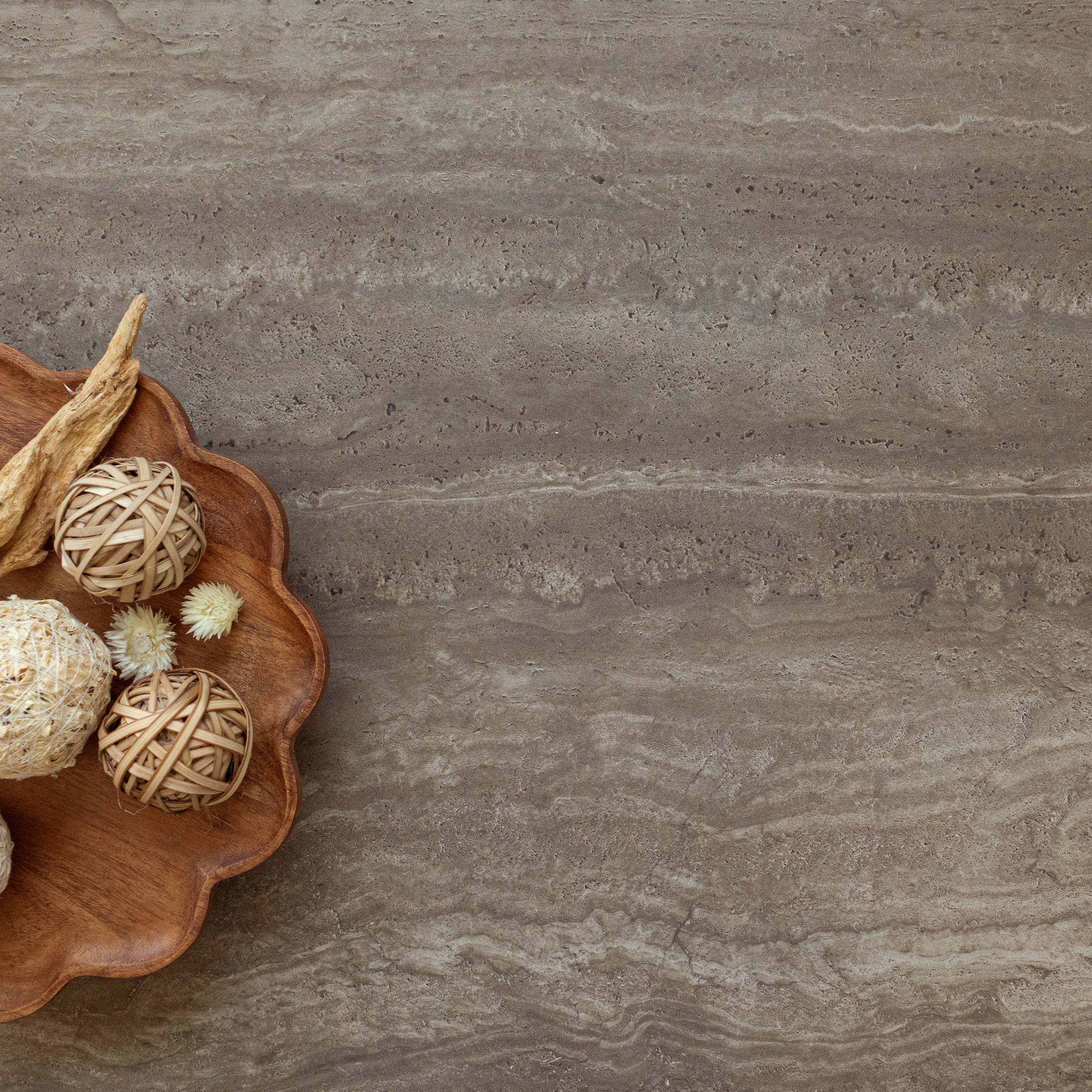 Earth-toned travertine-style surface with subtle natural veining and decorative wooden bowl with natural textures nearby