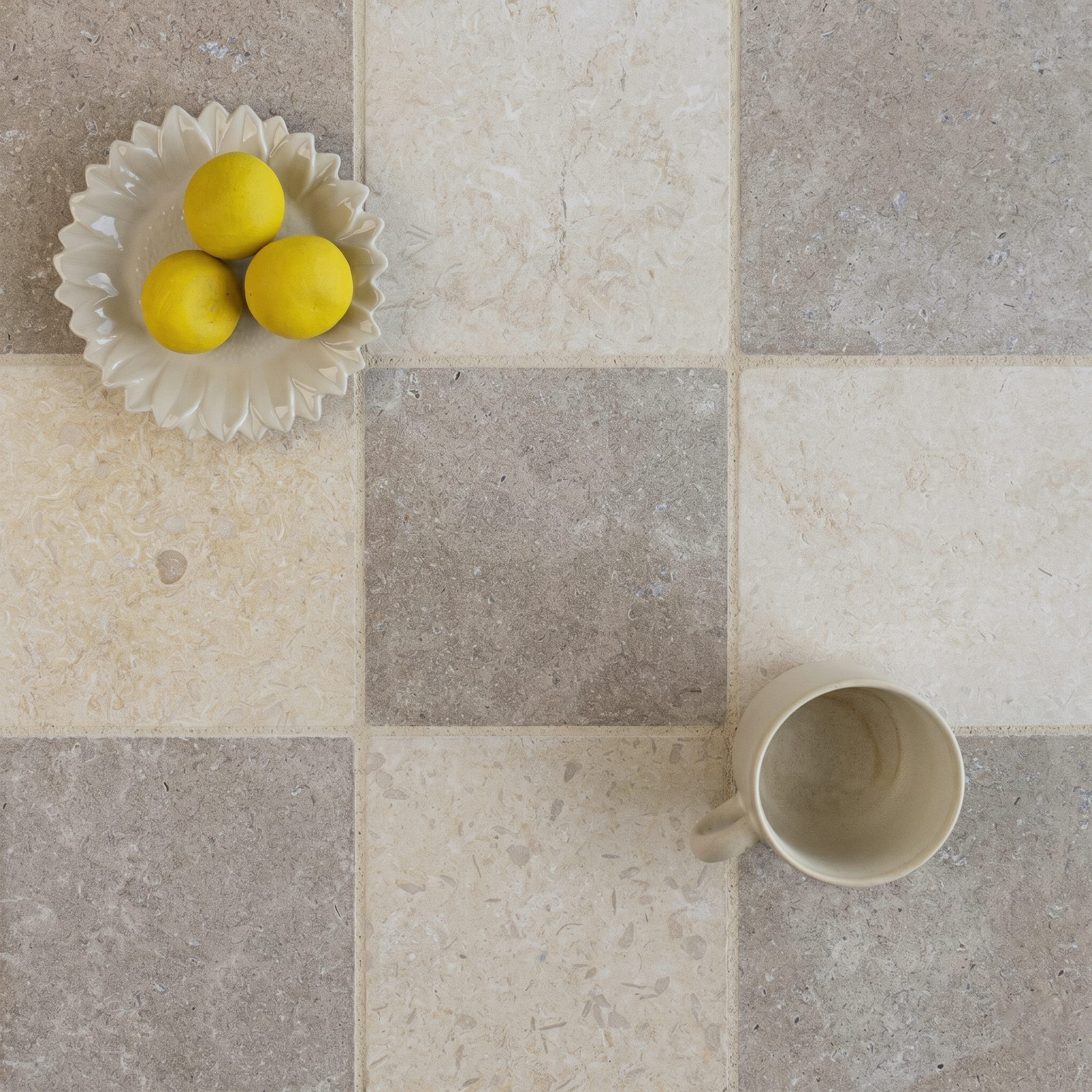 Beige and grey large format ceramic tiles arranged in a checkerboard pattern with a ceramic bowl and cup nearby