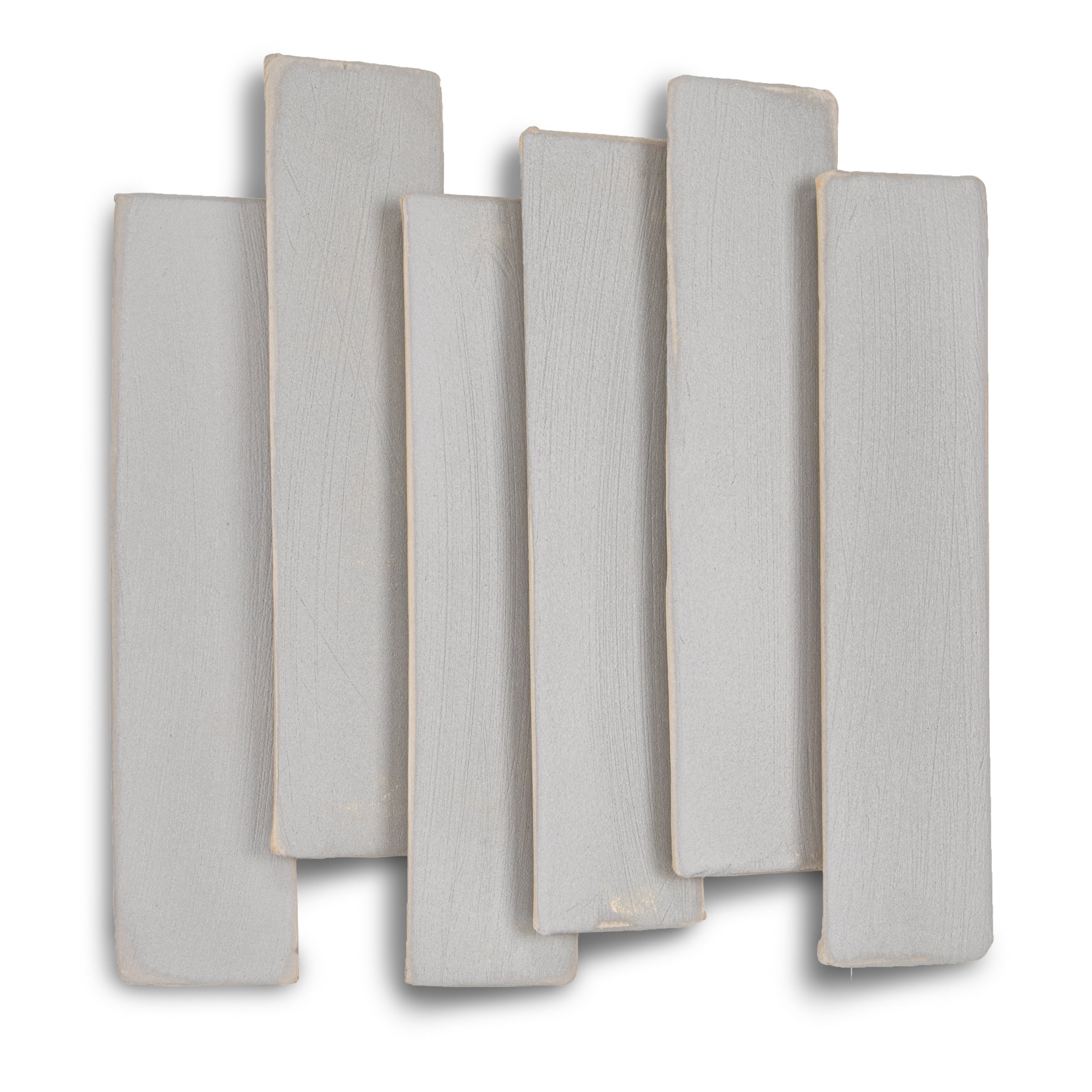 Seven narrow rectangular ceramic tiles in soft muted grey with subtle texture and irregular edges on white background