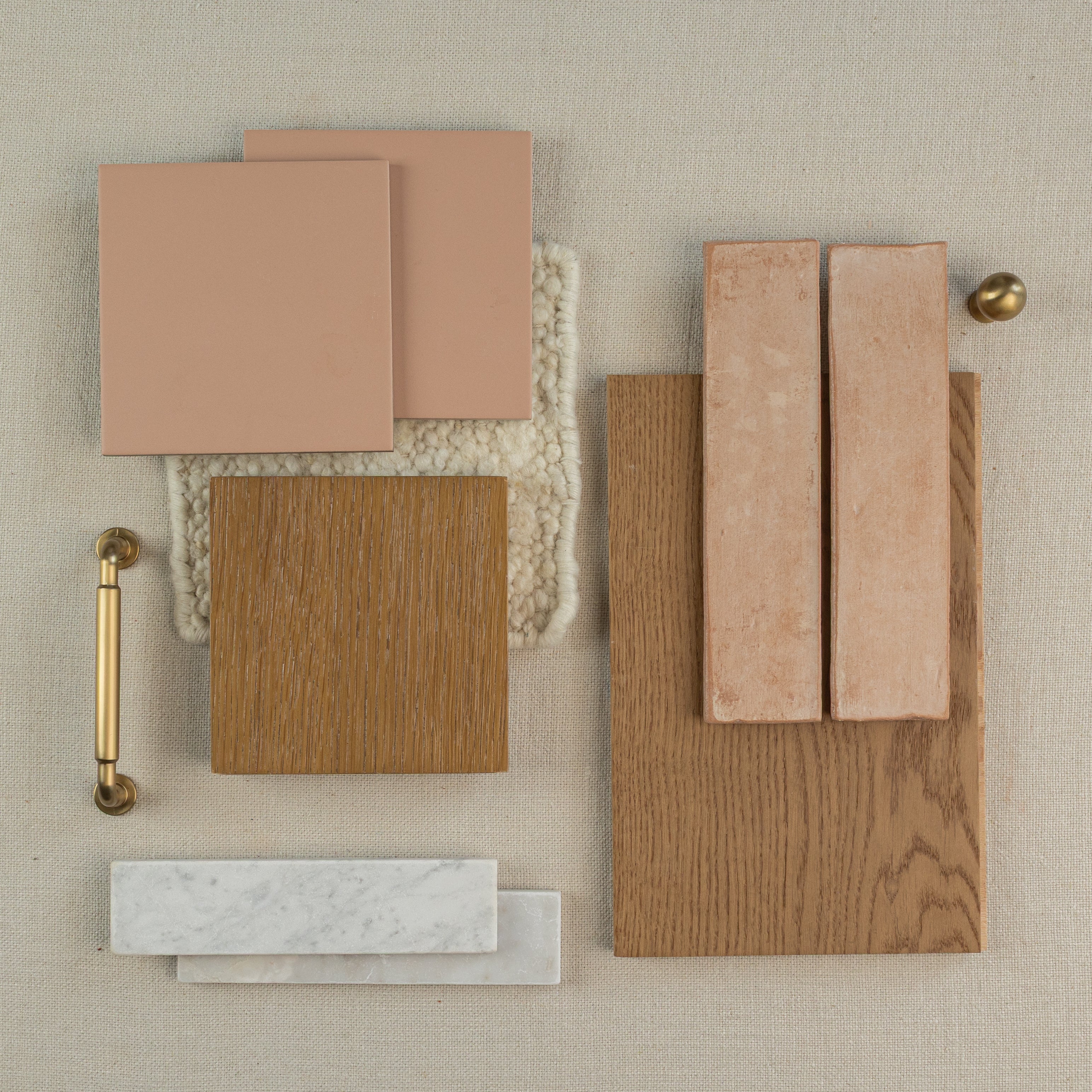 Arrangement of warm terracotta tiles, wood samples, marble pieces, and brass hardware on textured fabric surface