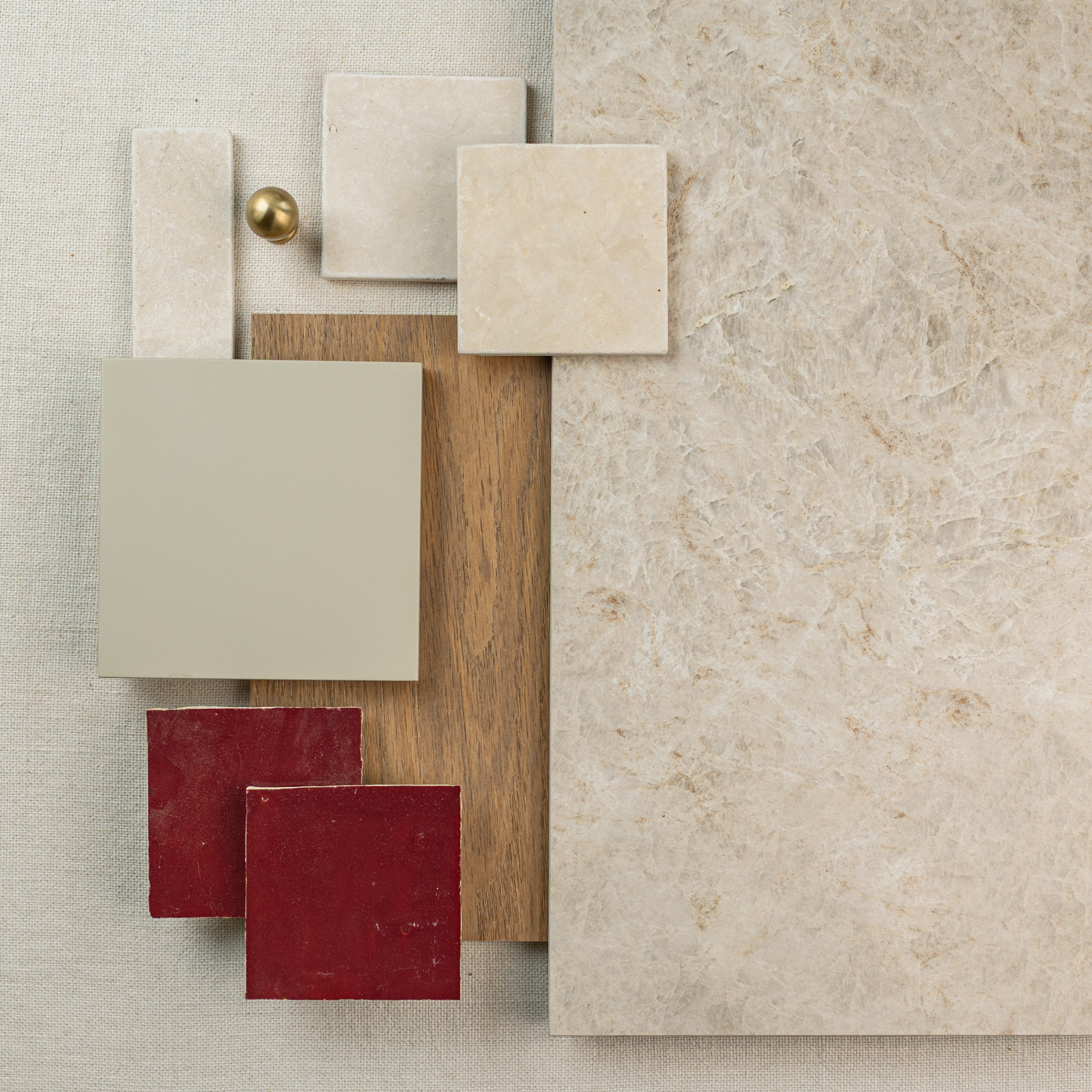 Arrangement of beige and red ceramic tiles with wood and fabric samples on a textured stone surface