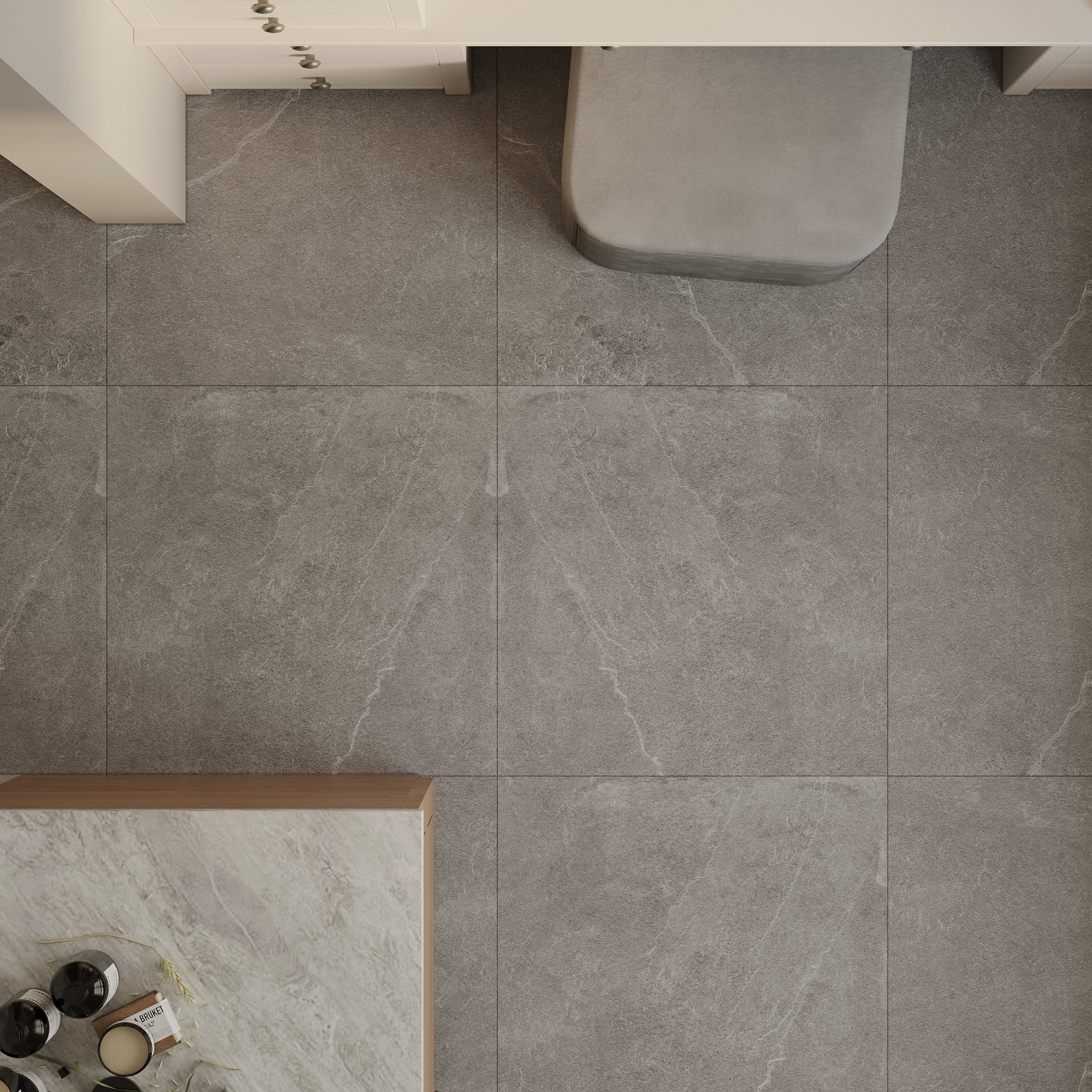 Overhead view of large format gray porcelain tiles with subtle white veining and a marble countertop edge nearby
