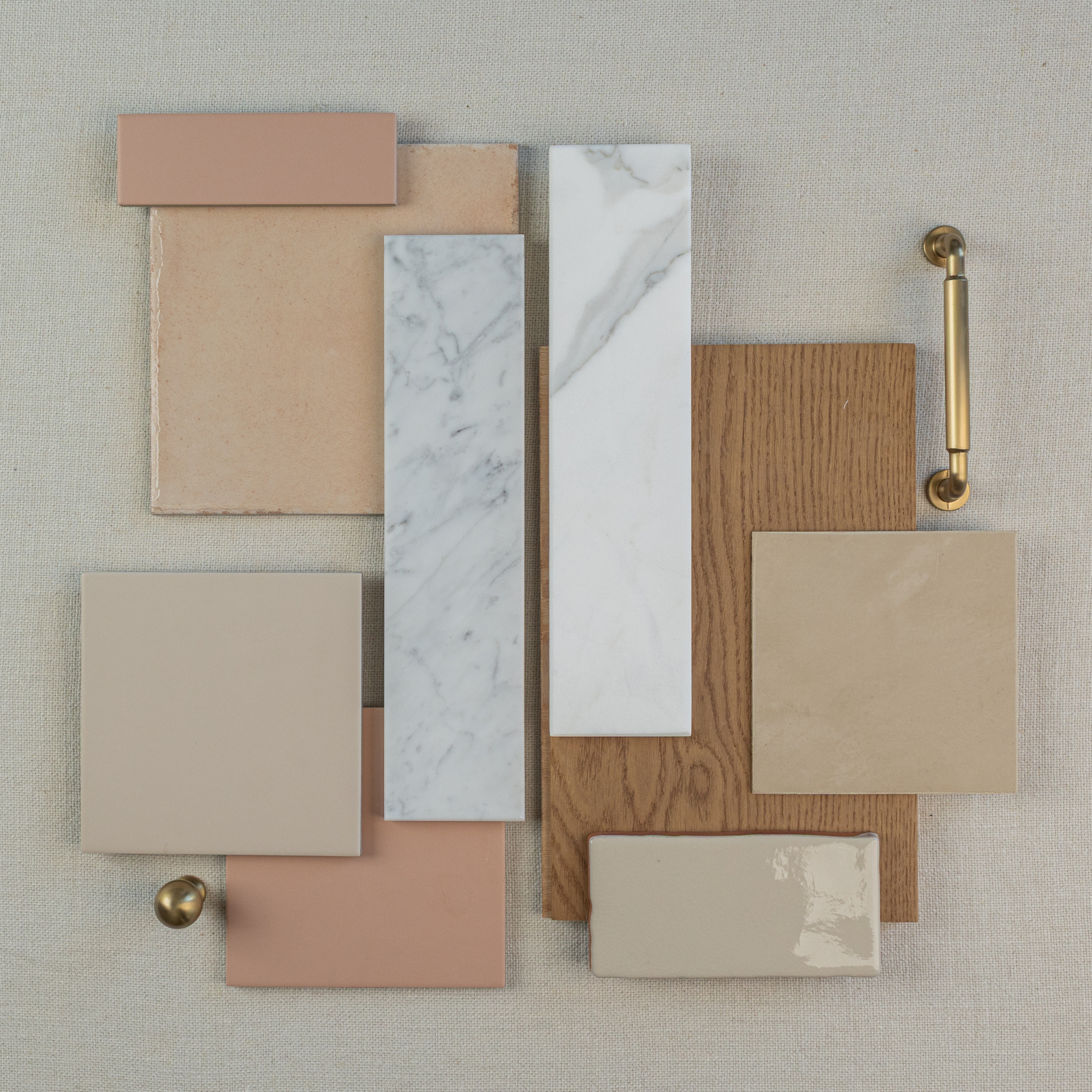 Layout of beige ceramic tiles, calacatta marble subway tiles, oak wood plank, brass hardware, and neutral color samples on fabric