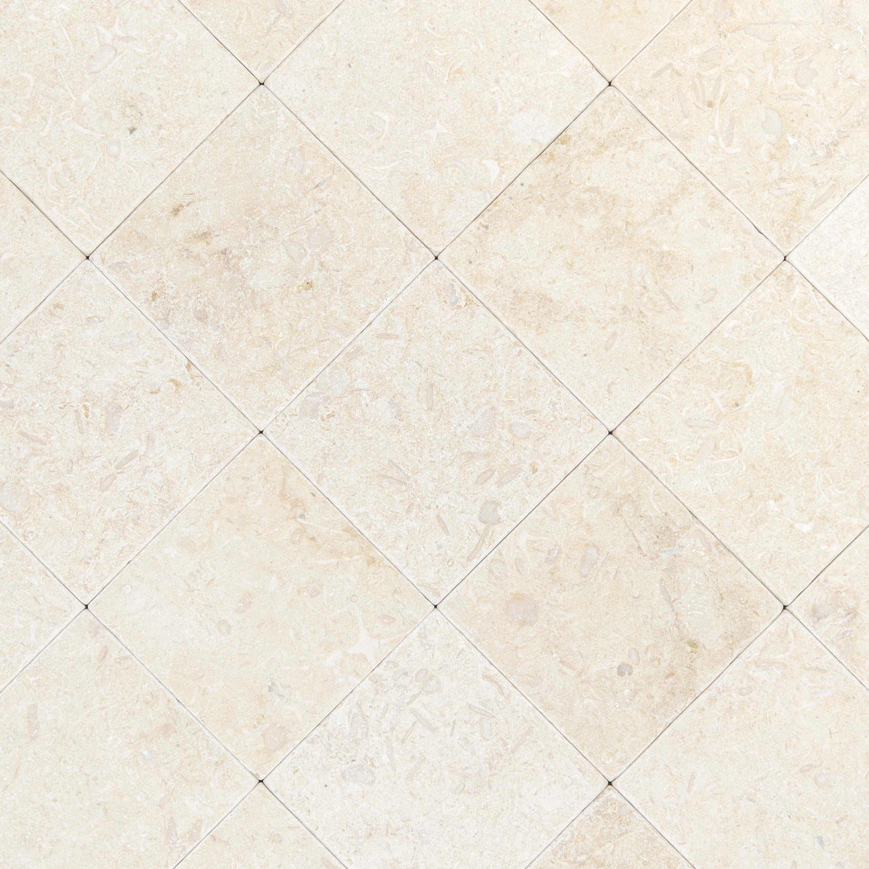 Light cream square stone tiles with tumbled edges and soft natural veining arranged in a diagonal pattern