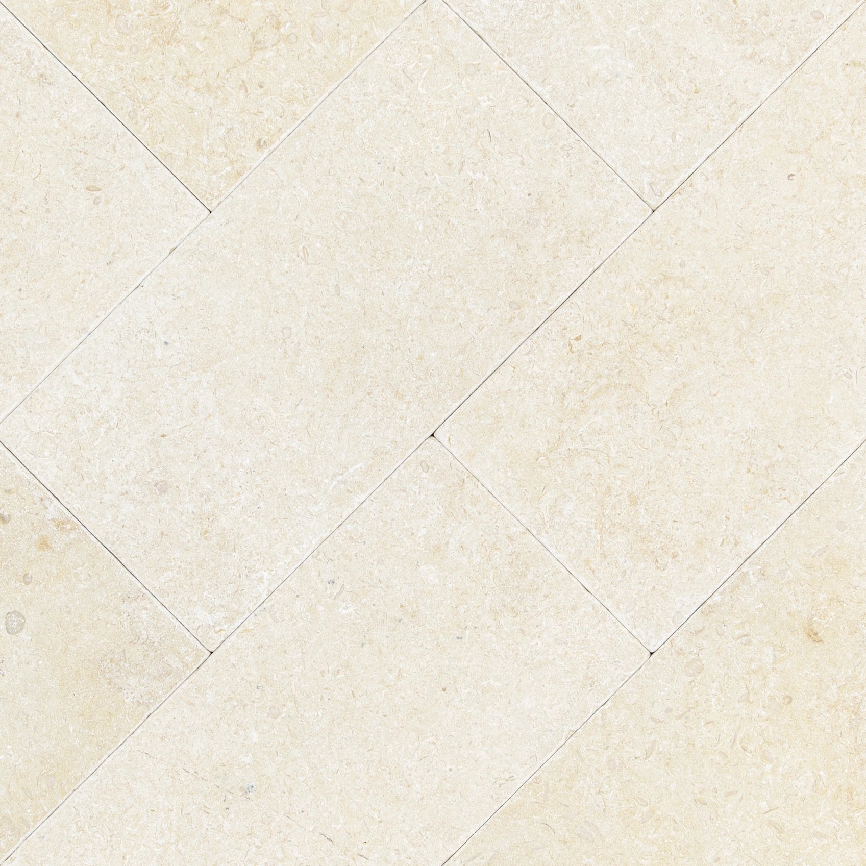Cream-colored tumbled stone tiles arranged in a staggered pattern with subtle natural texture and soft mineral details