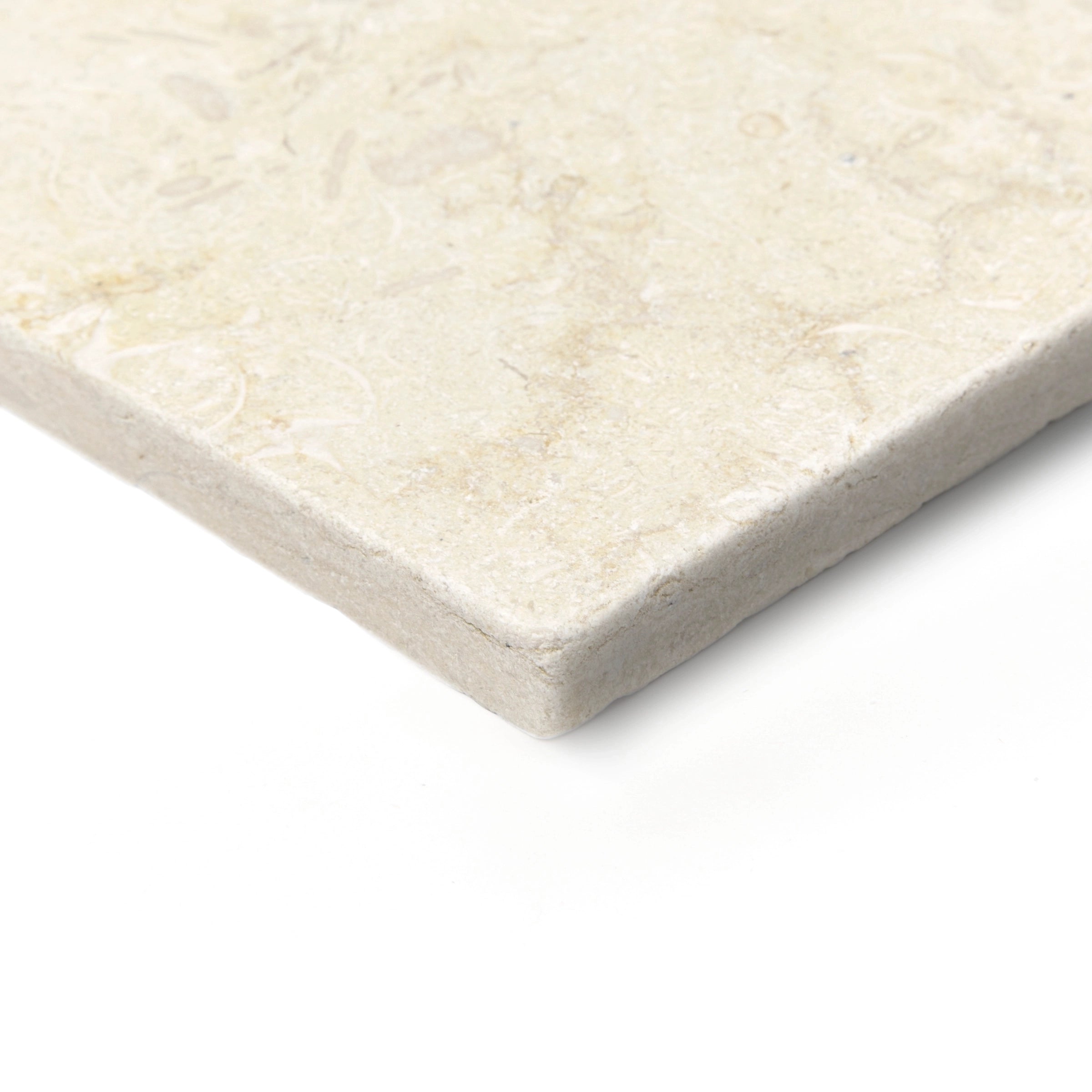 Close-up of a light beige tumbled stone tile with rounded edges and subtle natural fossilized patterns on the surface