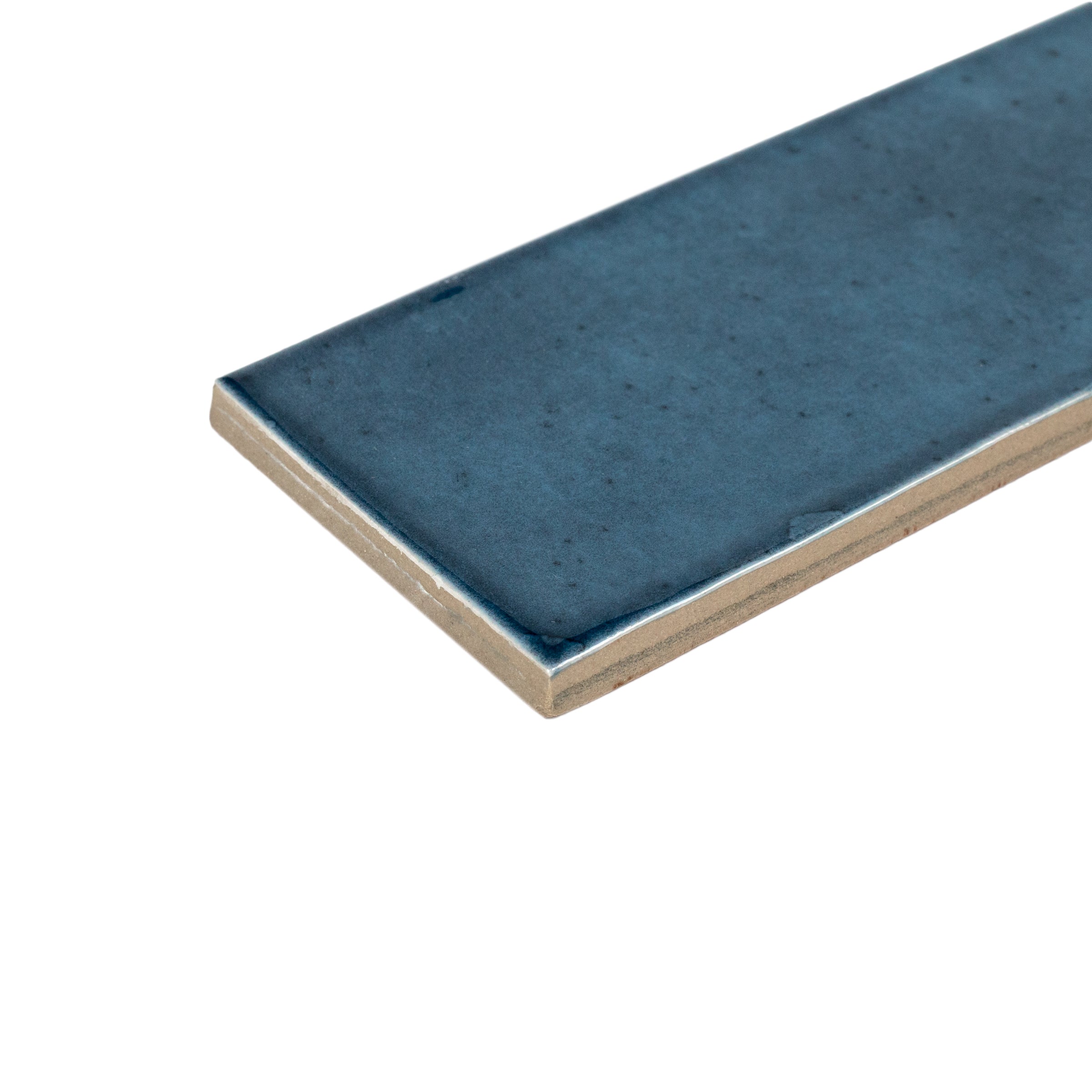 Close-up of deep blue glazed ceramic tile with smooth surface and slightly irregular edges on white background
