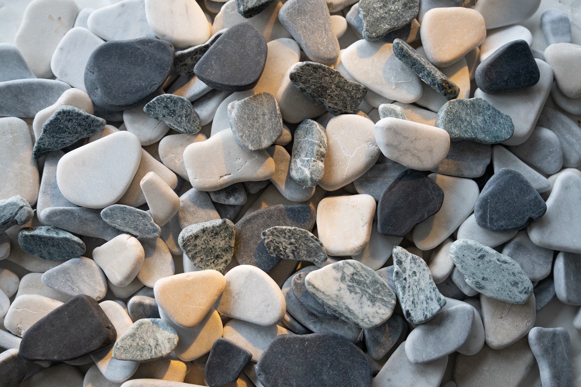 Natural assortment of smooth, rounded pebbles in shades of gray, white, cream, and black with varied textures