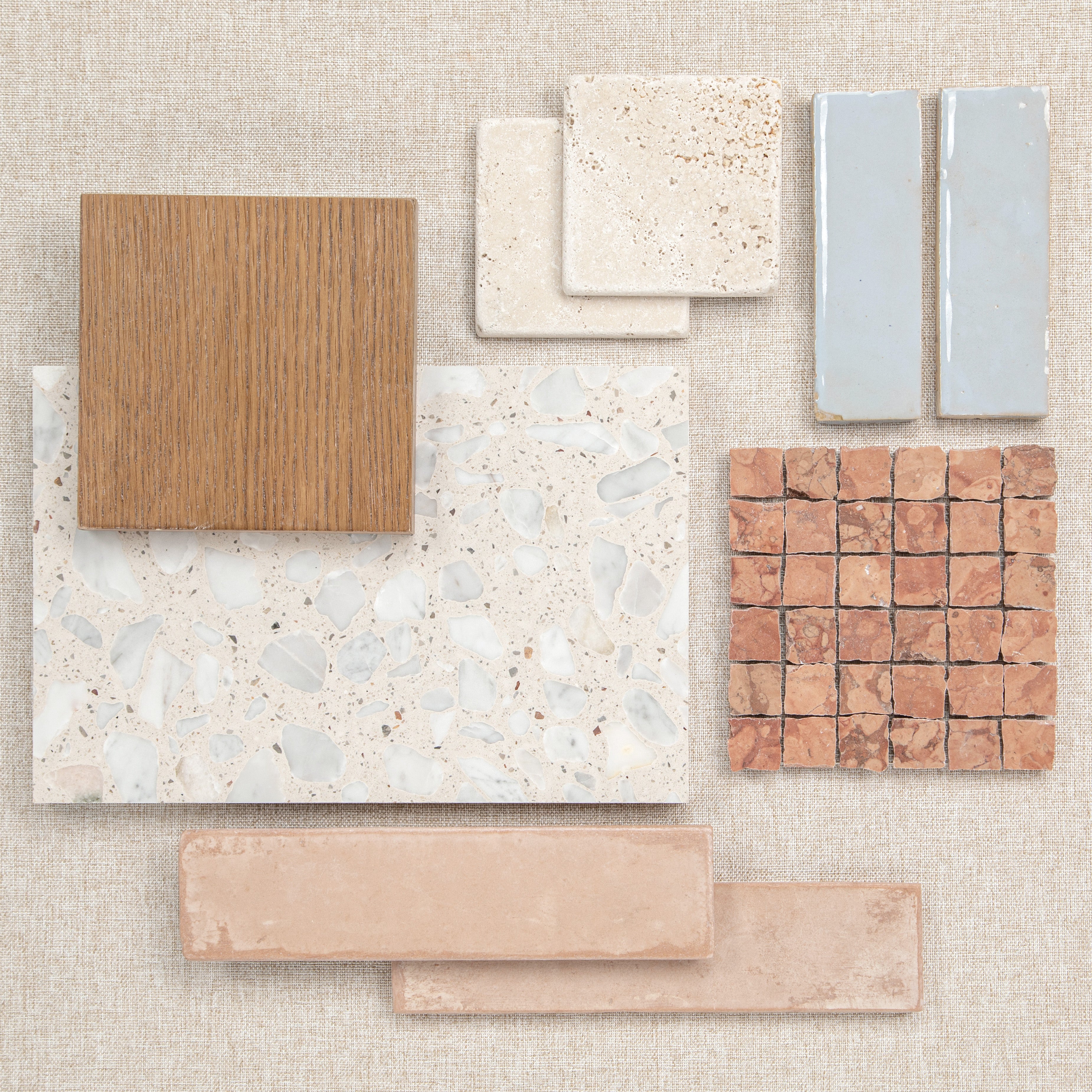 Various ceramic and porcelain tiles arranged on a neutral fabric surface showcasing natural tones and textures.
