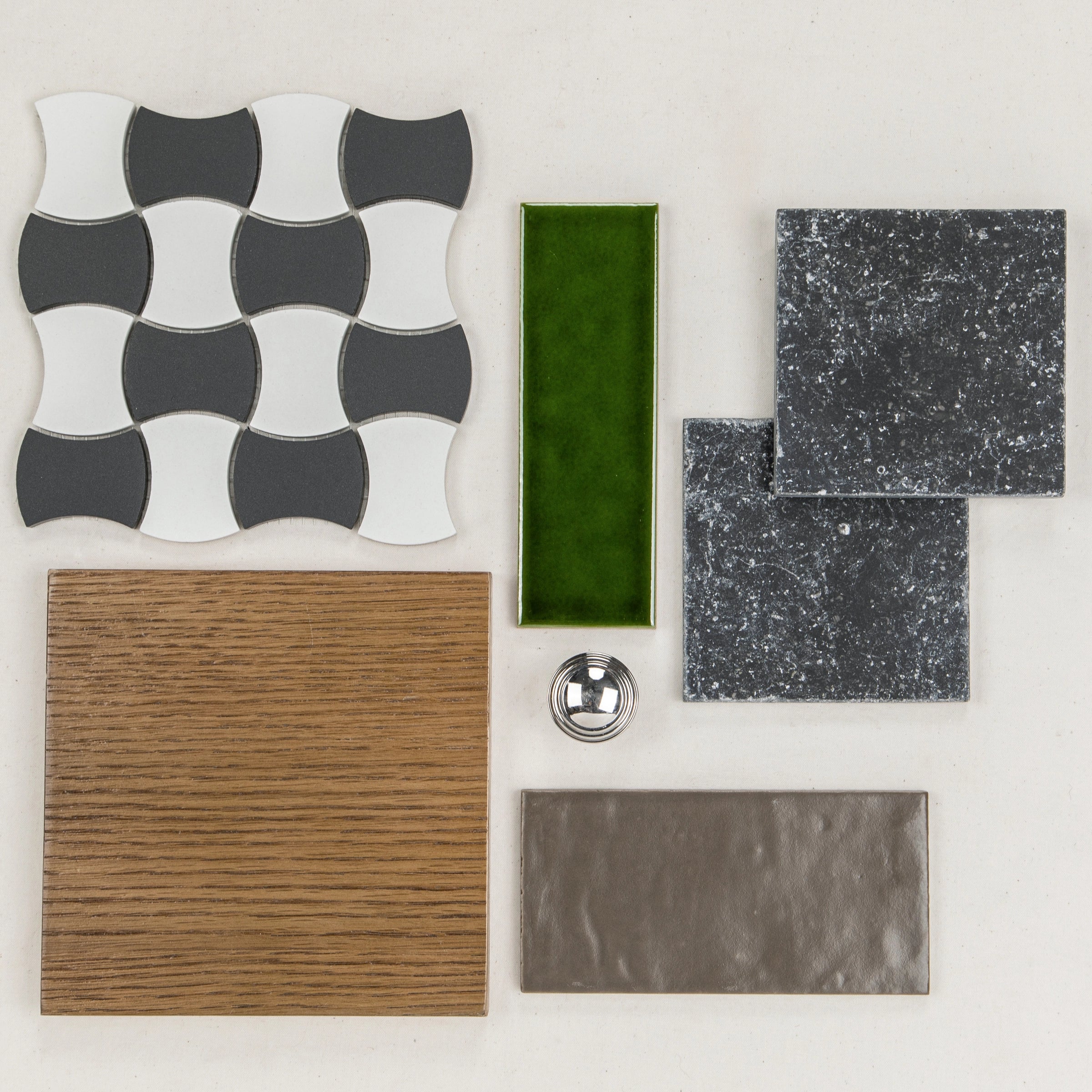 Curved black and white ceramic tile shapes, green glossy rectangle, textured black squares, wood grain and metallic tile samples with a knob