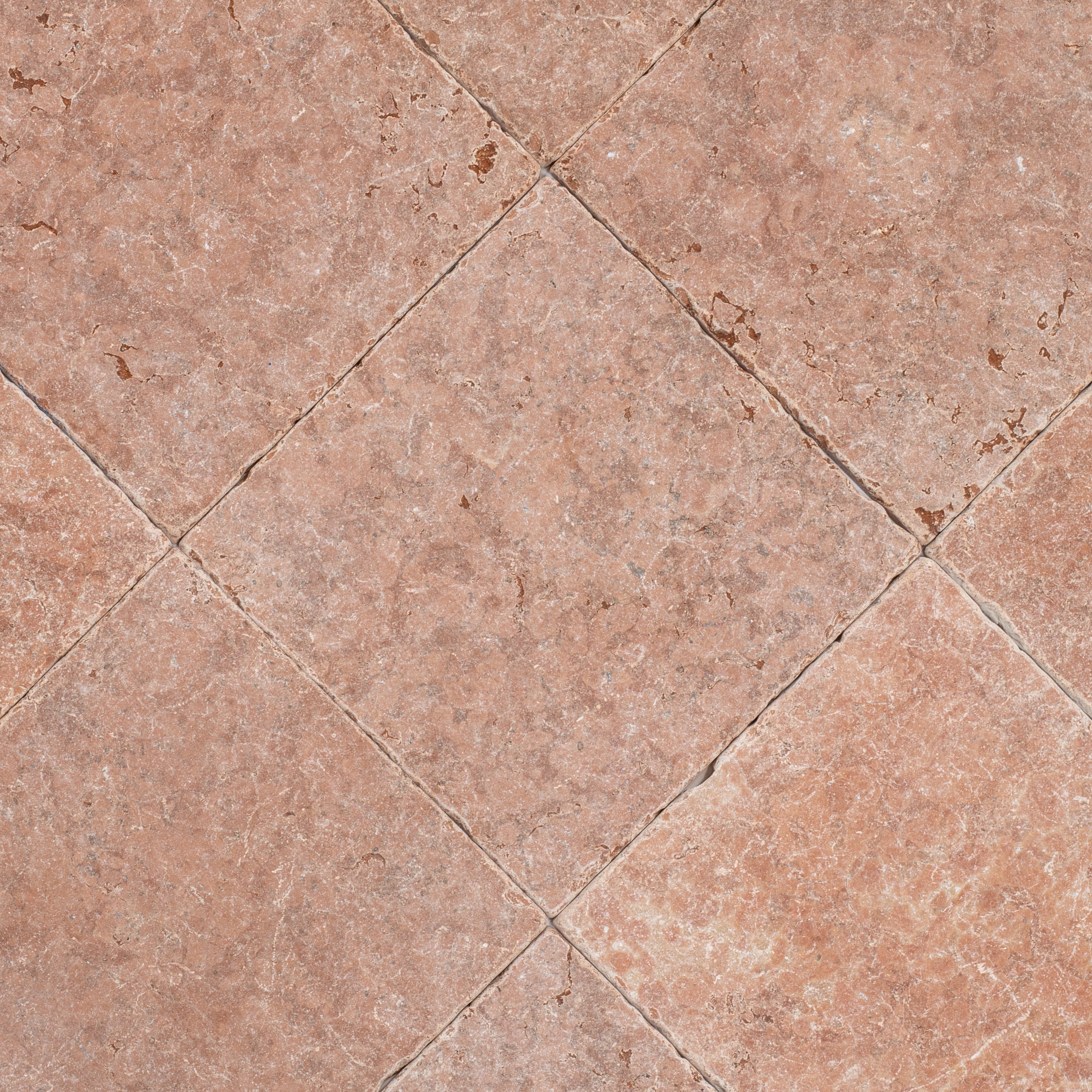 Close-up of warm terracotta tiles with a tumbled surface and natural mottled texture arranged in a diagonal pattern