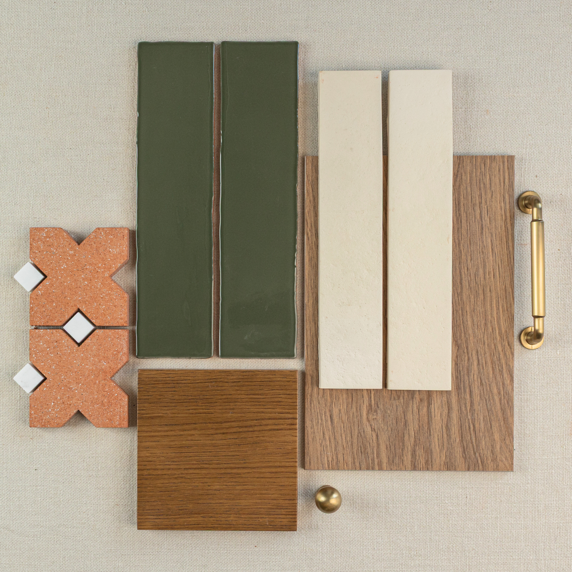 Collection of terracotta patterned tiles, glossy olive-green tiles, light beige tiles, wood plank, and brass handle on fabric background