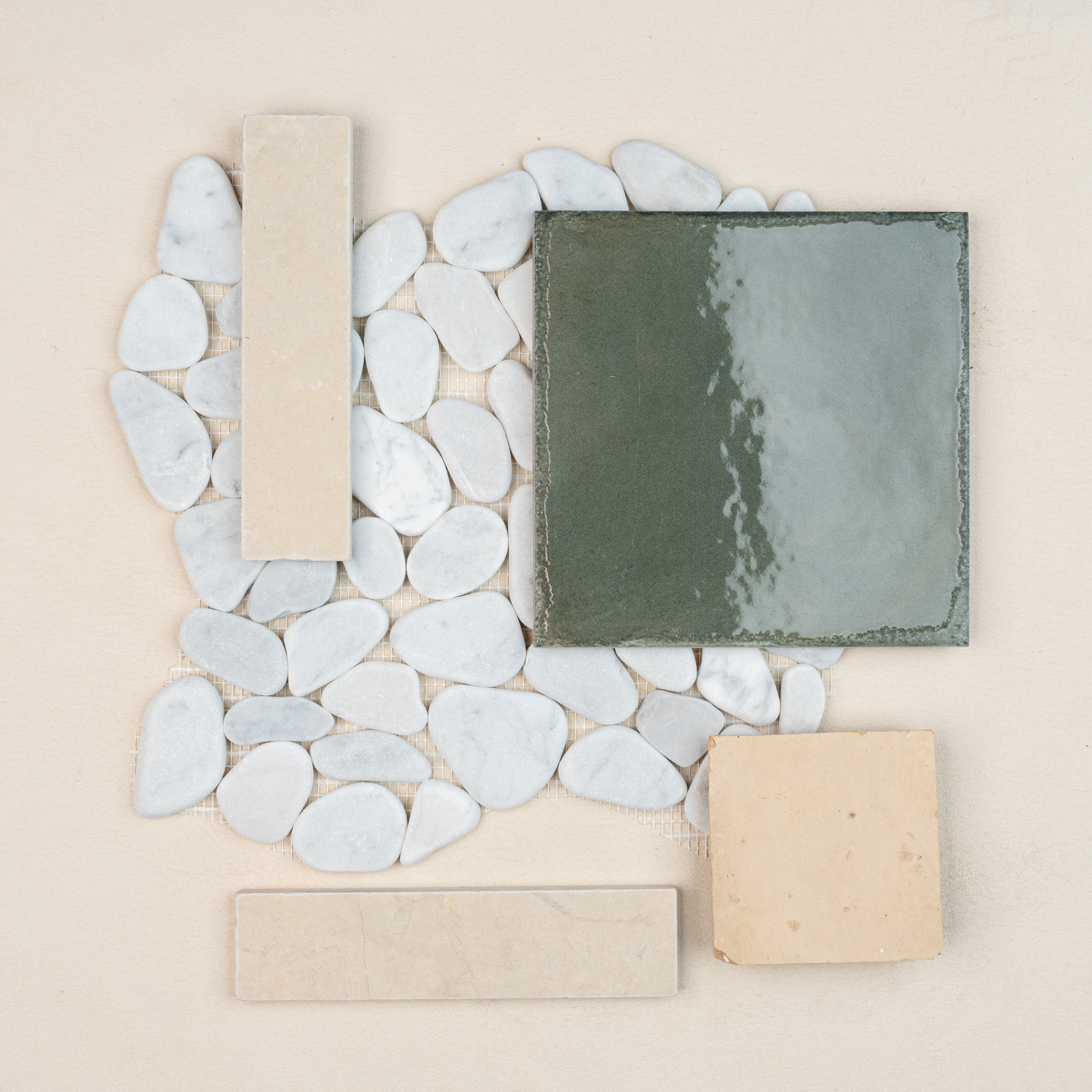 Arrangement of glossy green ceramic tile, beige ceramic samples, and white stone pebbles on neutral fabric surface