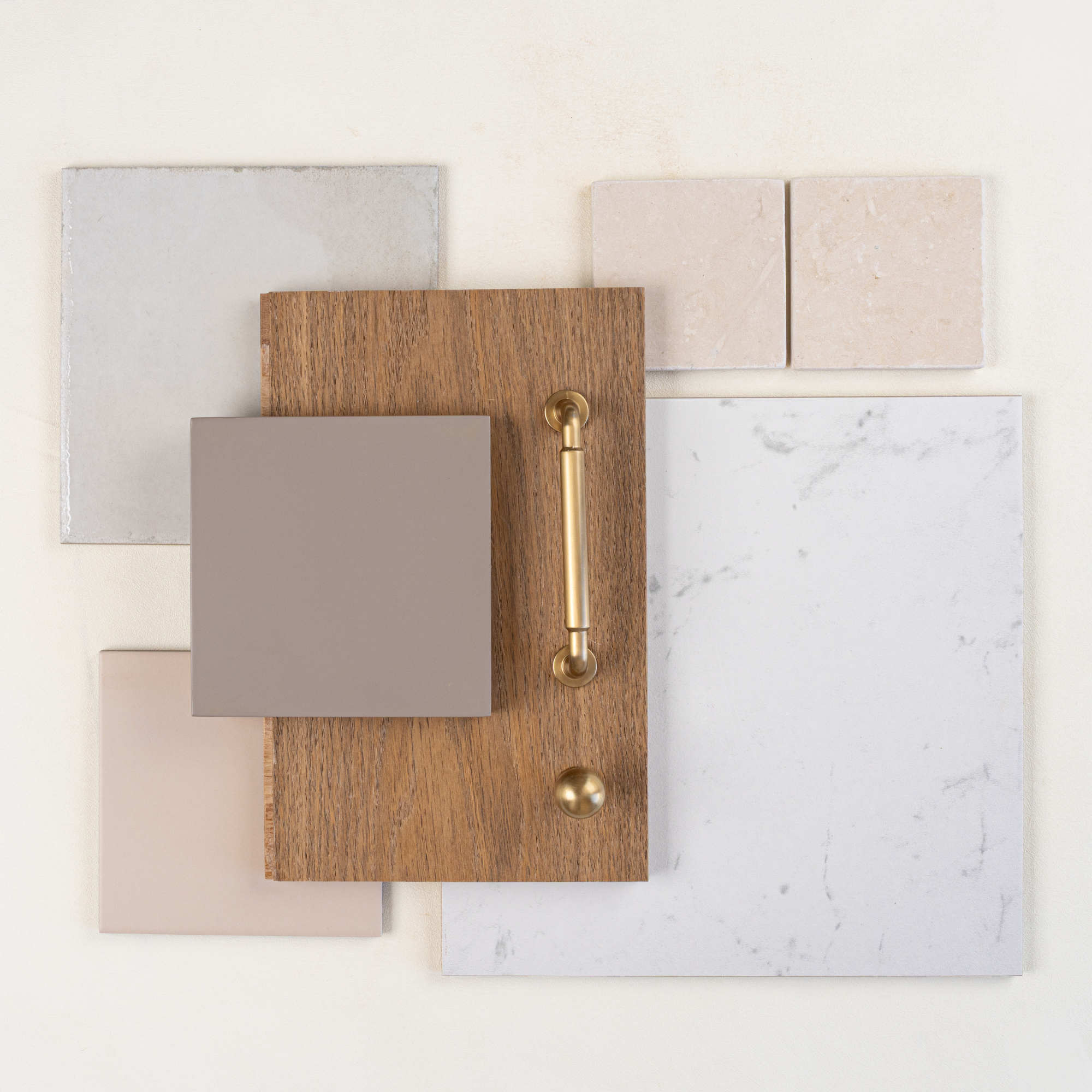 Arrangement of wood panel with brass handle and knob, beige ceramic tiles, and white marble tile on light background