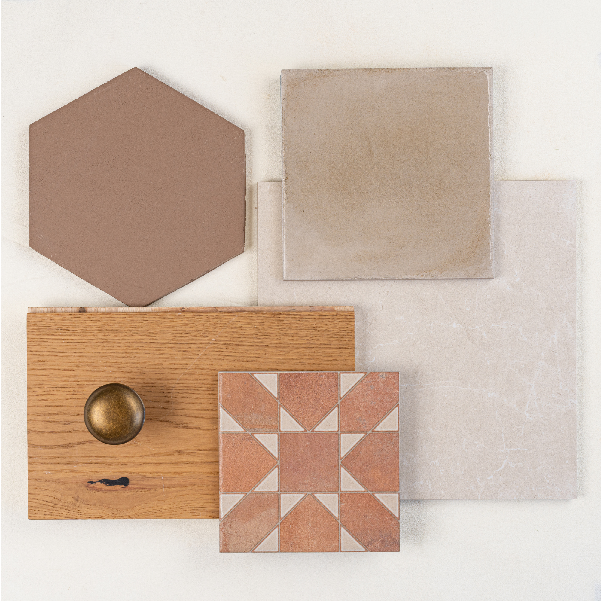  assortment of tiles including matte hexagon, patterned terracotta, beige stone, and wood with brass knob on white surface