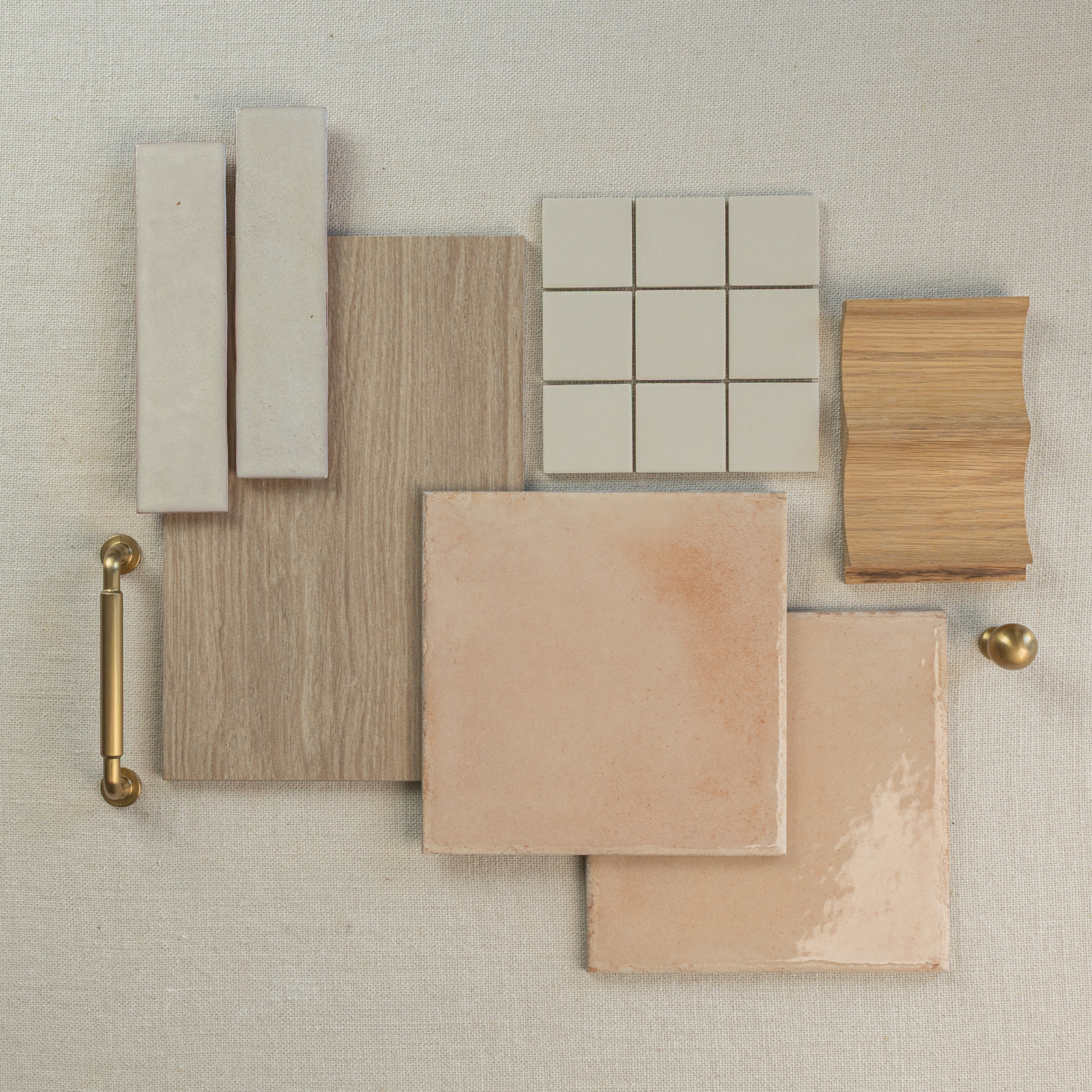 Flat layout of beige porcelain tiles, light oak wood samples, smooth ceramic tiles, and brass hardware on neutral linen background
