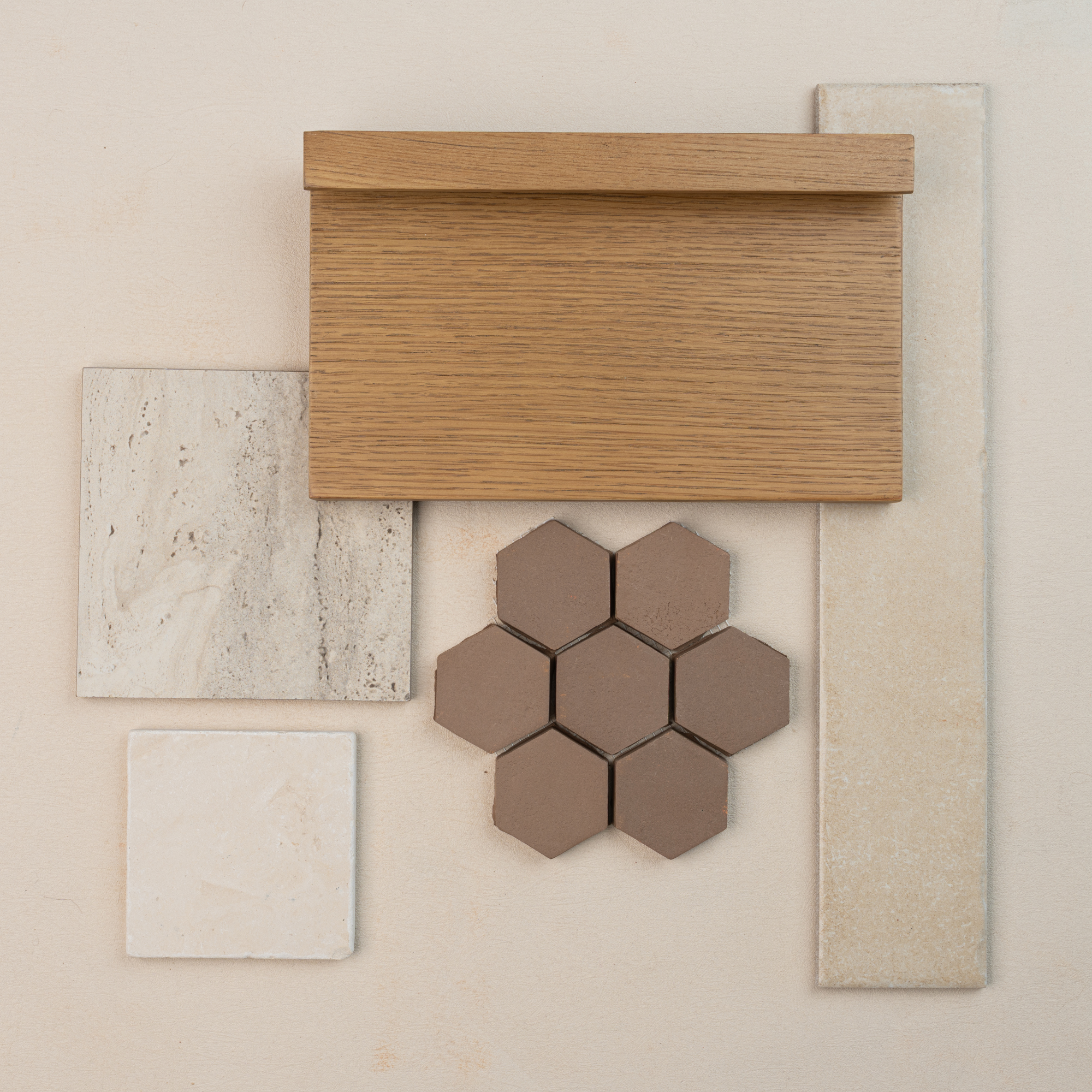 Arrangement of oak wood sample, beige rectangular and square tiles, natural stone tile, and brown hexagonal ceramic tiles on light surface