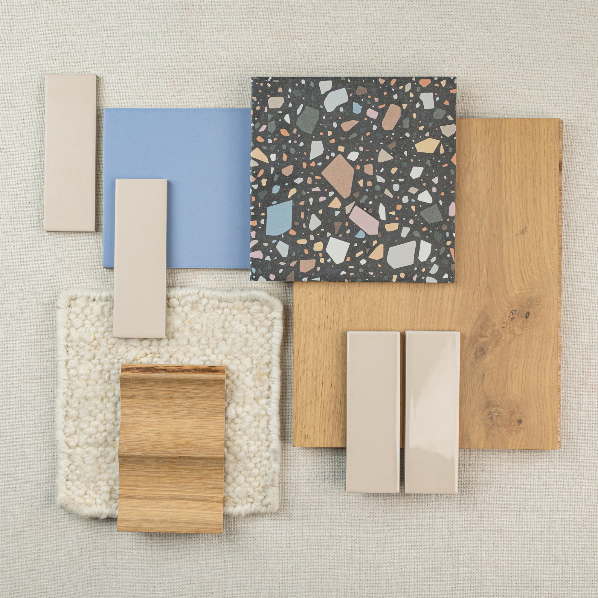 Selection of tile, engineered wood flooring, and fabric samples arranged on a neutral background for design inspiration