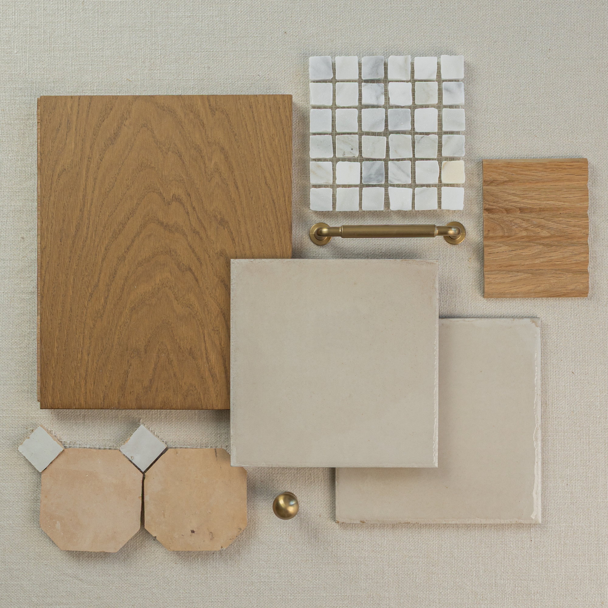 Flat arrangement of natural oak wood samples, beige ceramic tiles, white mosaic tiles, terracotta hex tiles, and brass hardware on neutral fabric