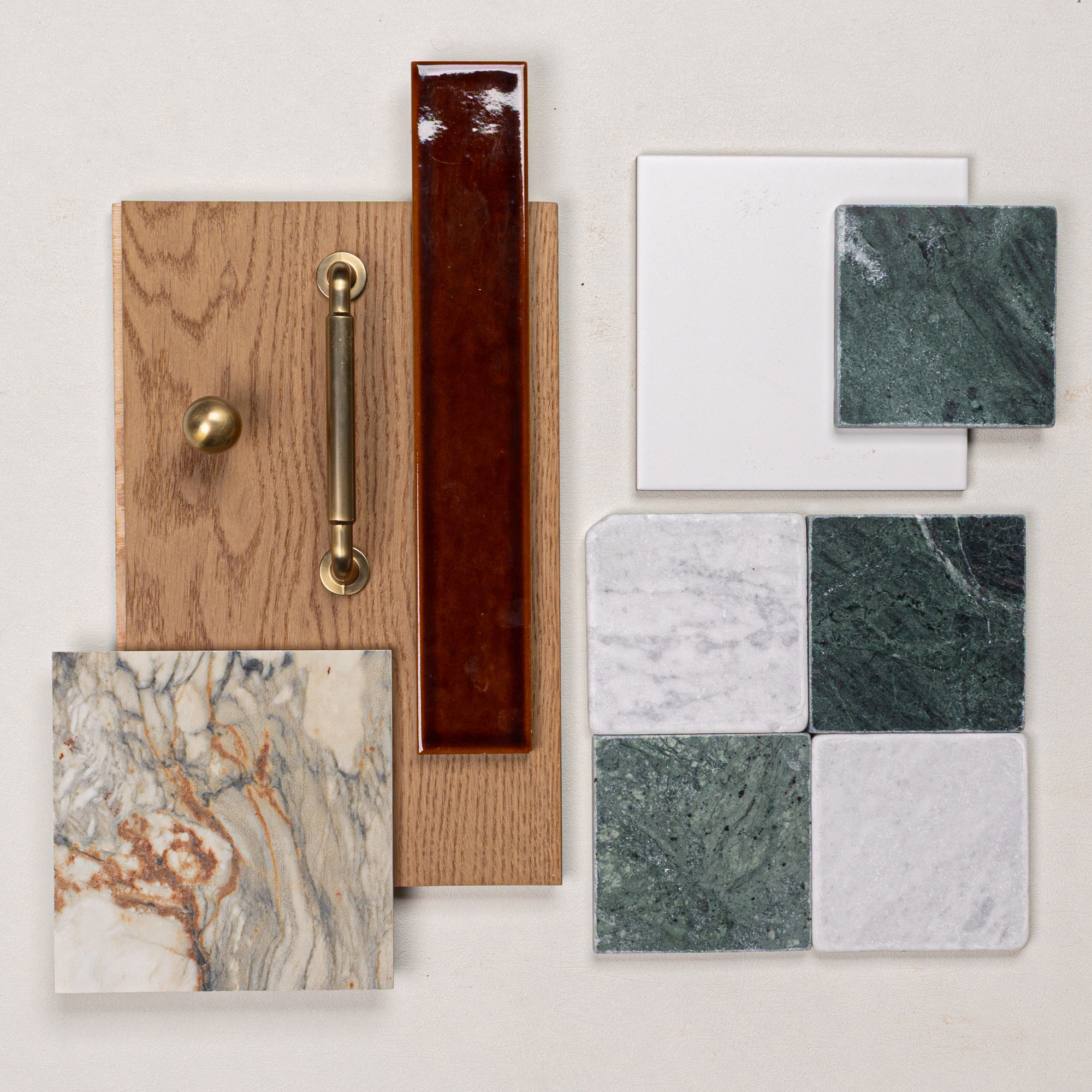 Oak wood sample with brass hardware alongside green and white marble and ceramic tiles on a light background