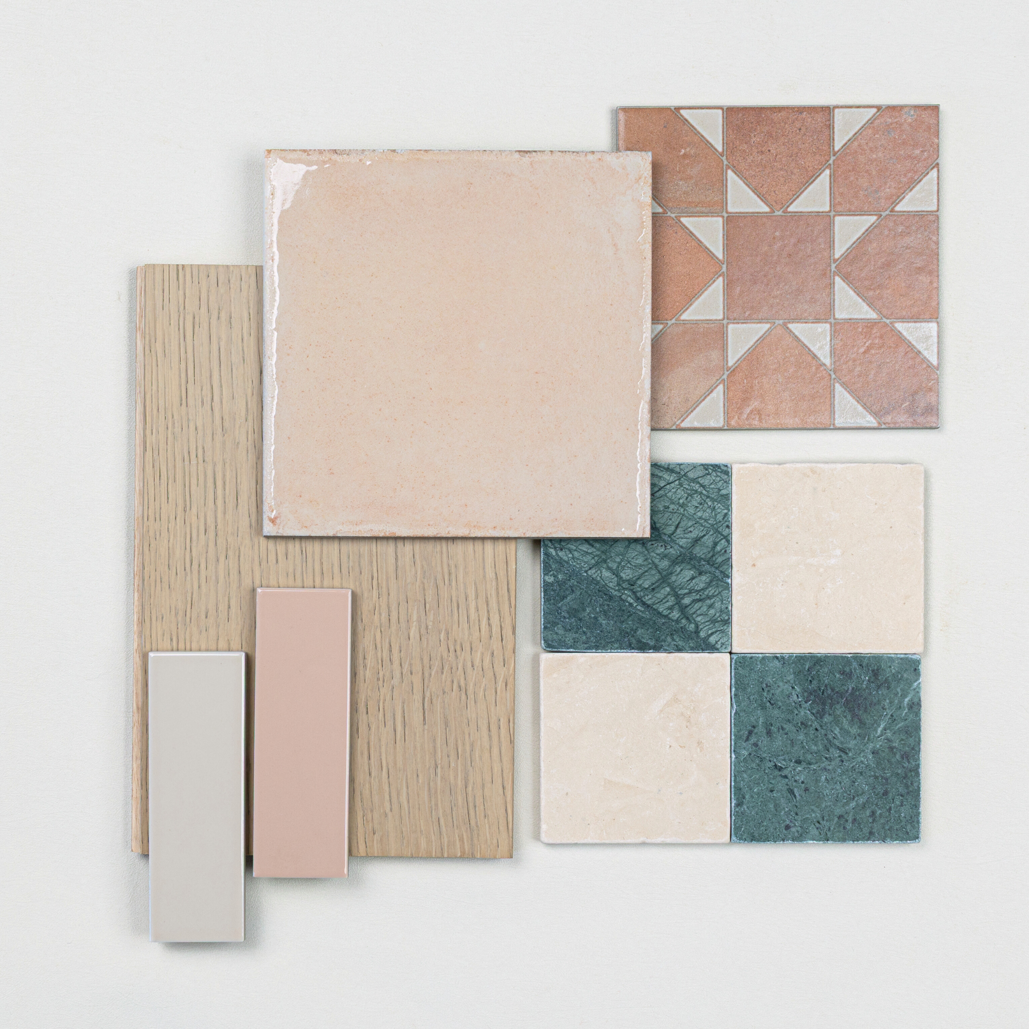Arrangement of terracotta patterned, beige ceramic, green and cream porcelain tiles with light oak wood and neutral color samples on white background