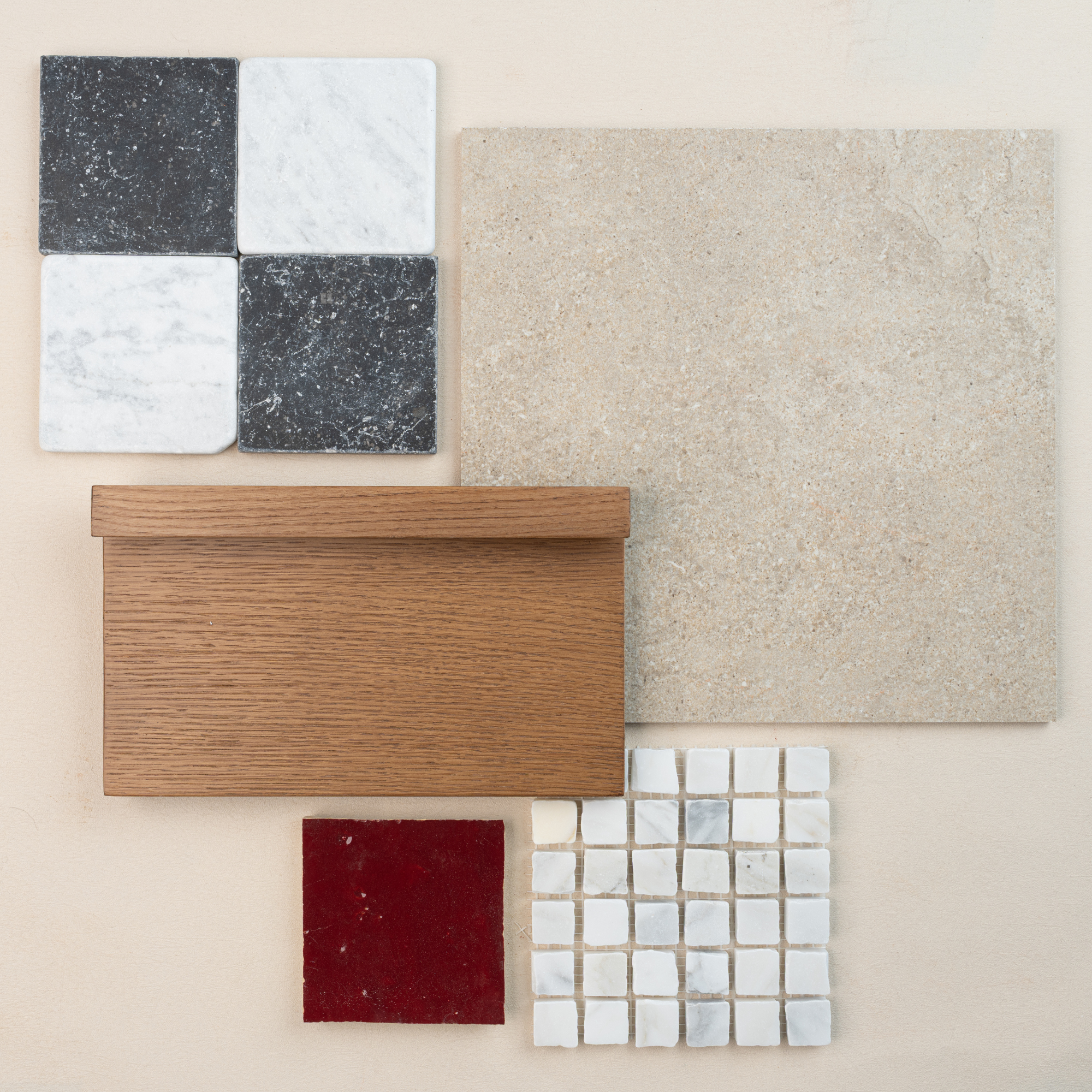 Assortment of natural stone tiles, oak wood sample, beige large format tile, and small white mosaic tiles on neutral background