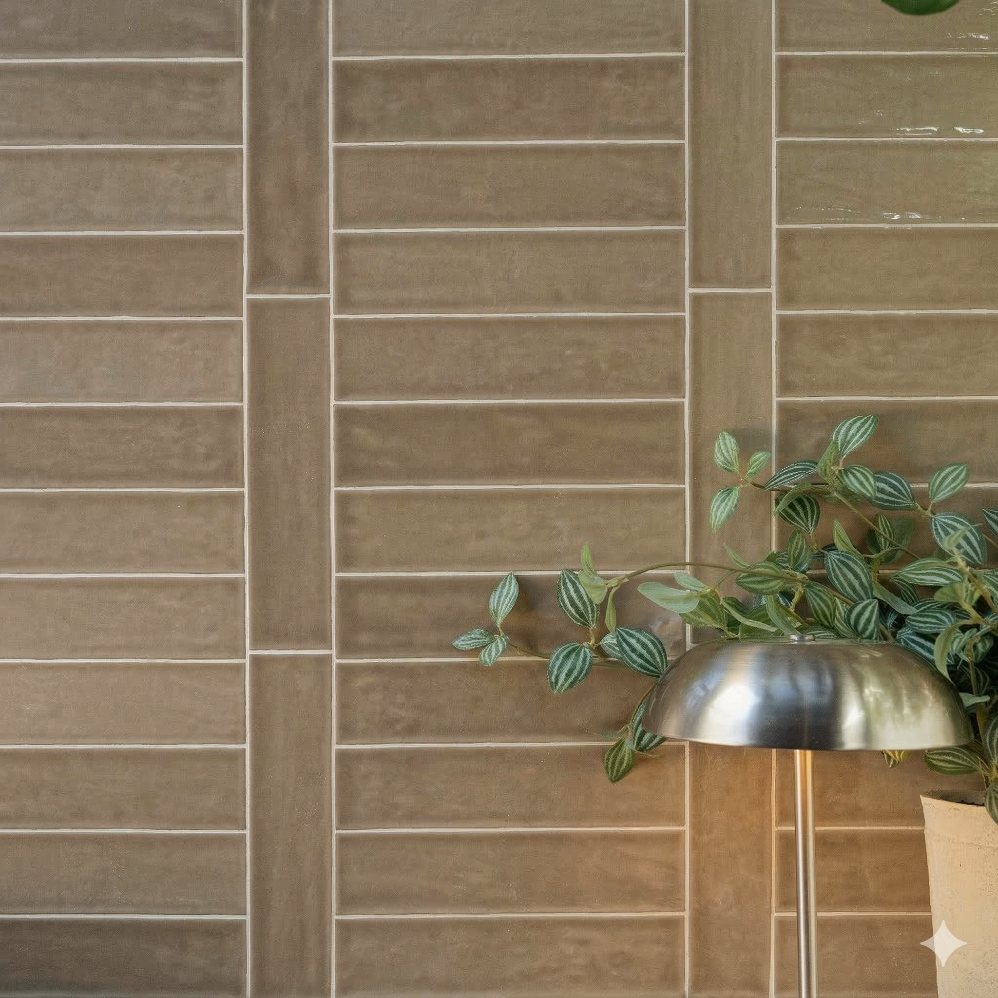 Glossy rectangular ceramic tiles in warm sand tones with a modern metallic lamp and green leafy plant nearby
