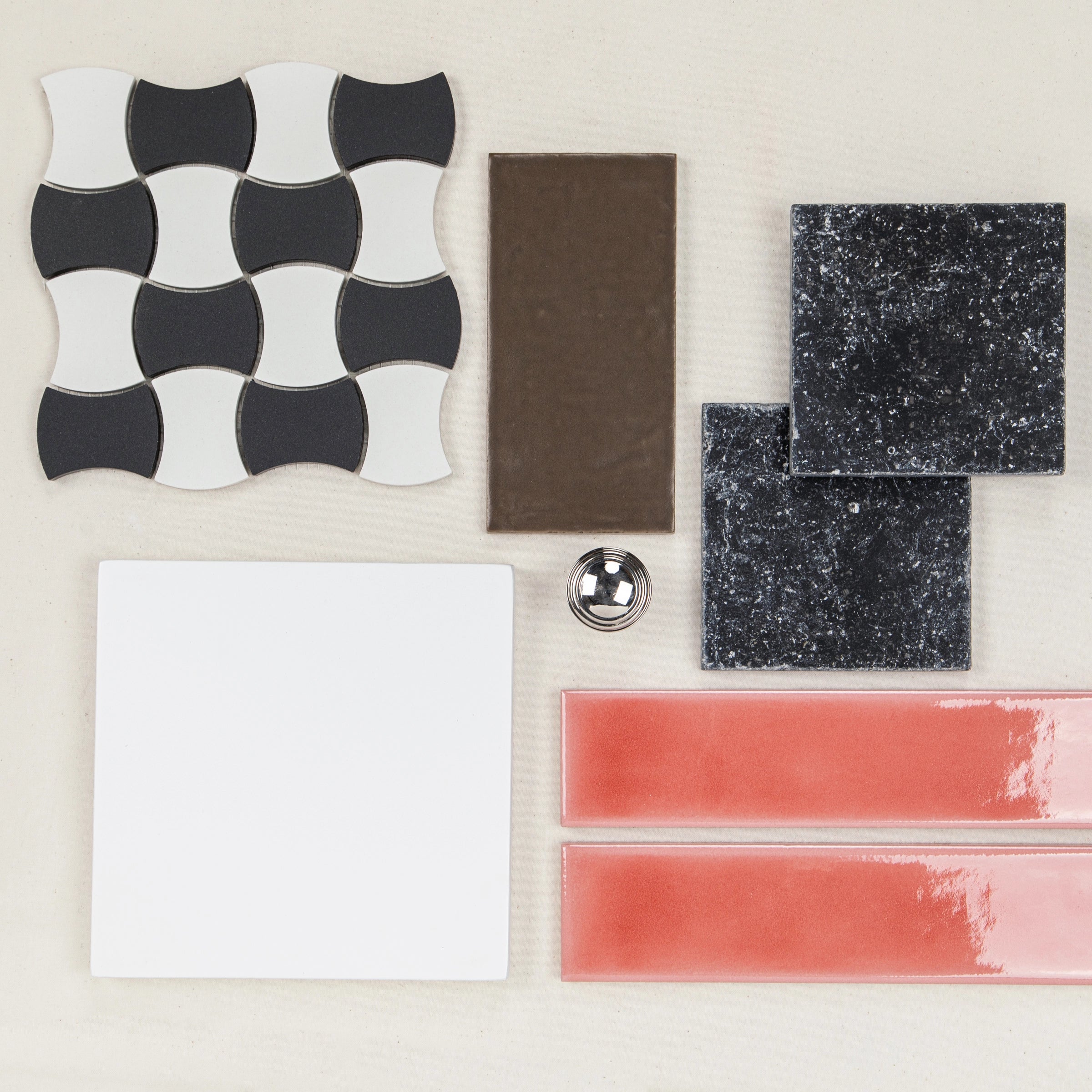 Assorted ceramic and porcelain tiles in black, white, brown, coral, and speckled dark gray tones arranged on a light background
