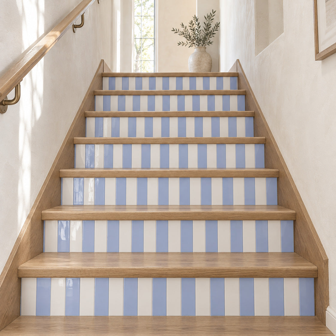 Wood staircase with blue and white striped tile risers and a vase by a sunlit window