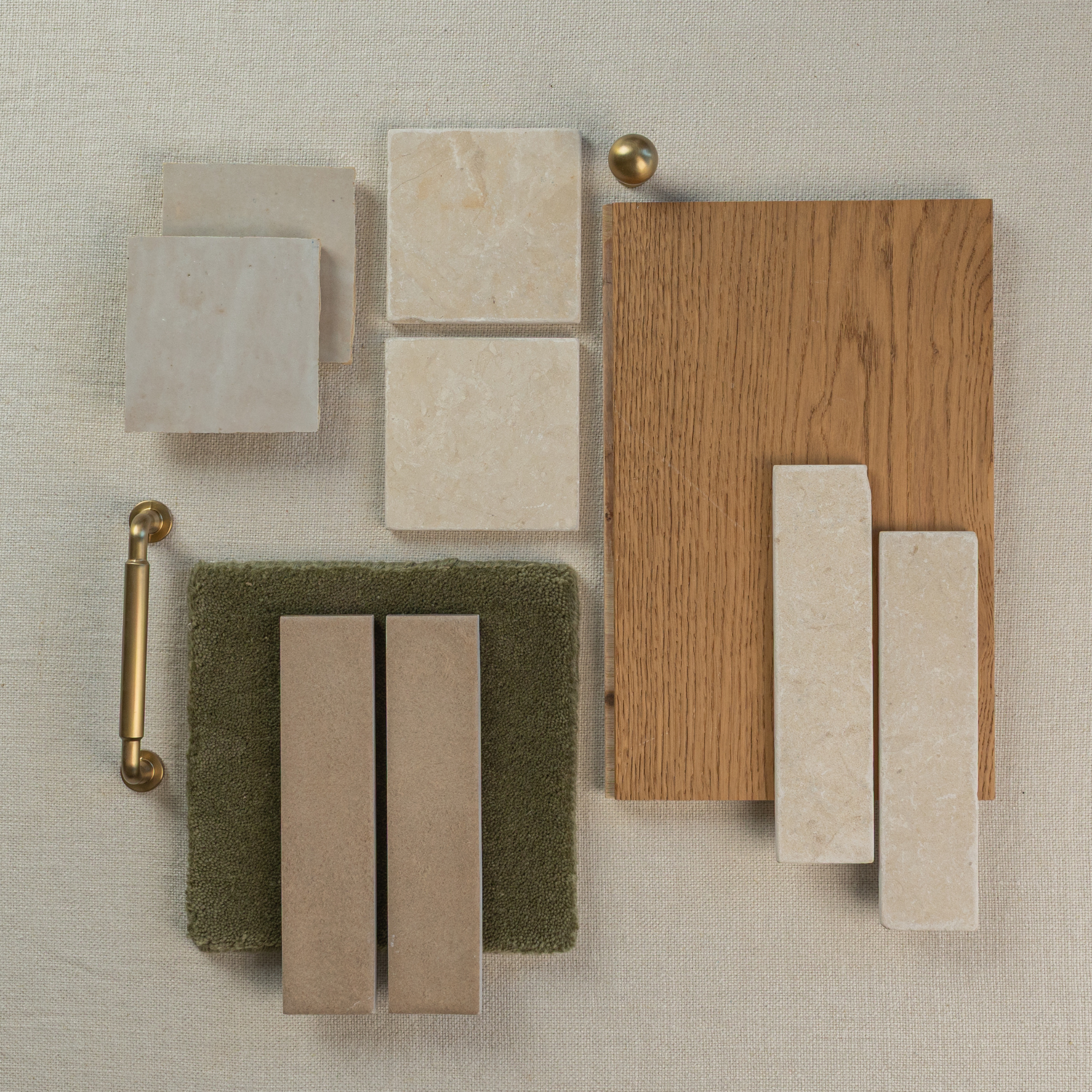 Flat lay of beige ceramic and marble tiles, oak wood veneer, textured green fabric, and brass hardware on neutral linen