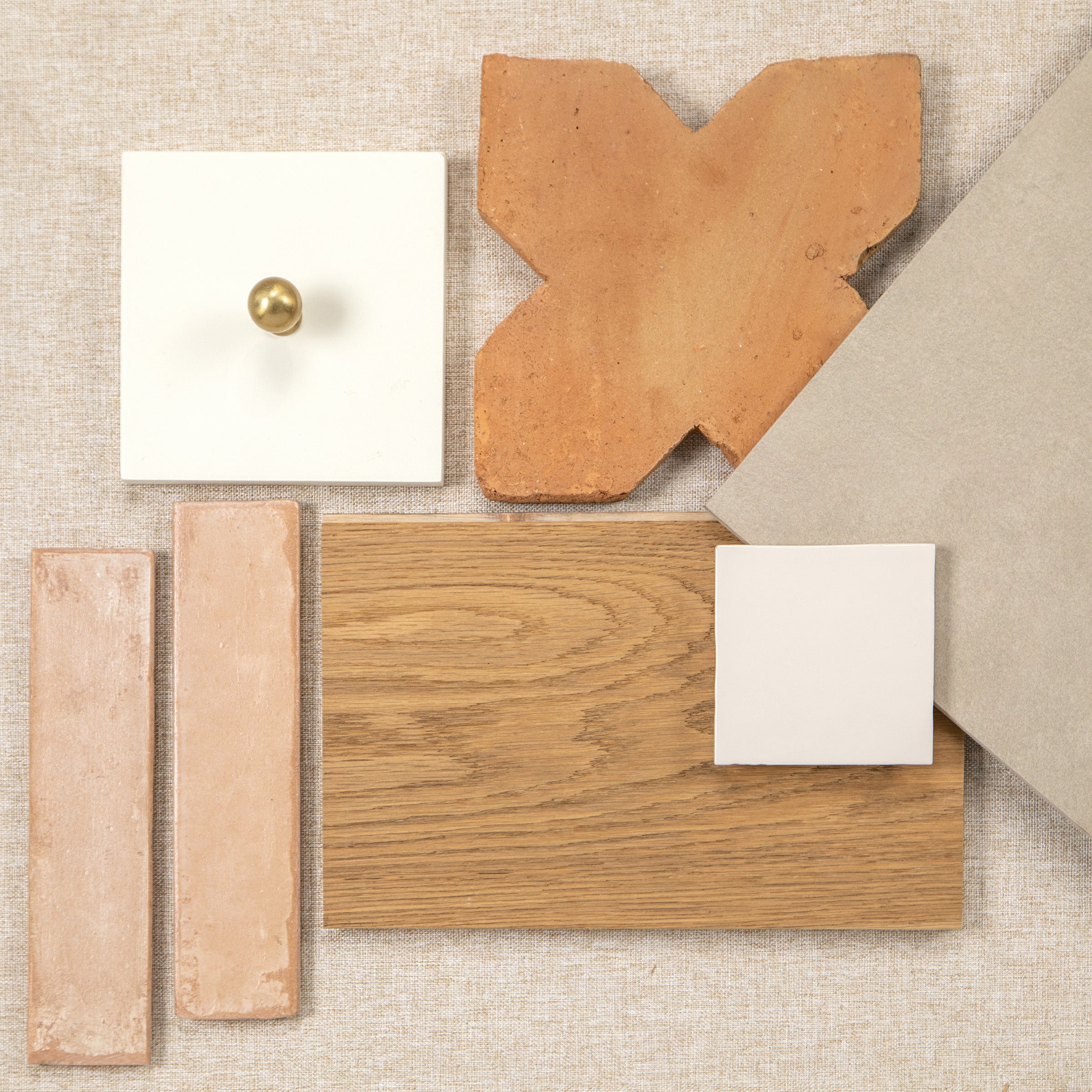 Flat lay of neutral tile, terracotta, wood flooring, and stone samples