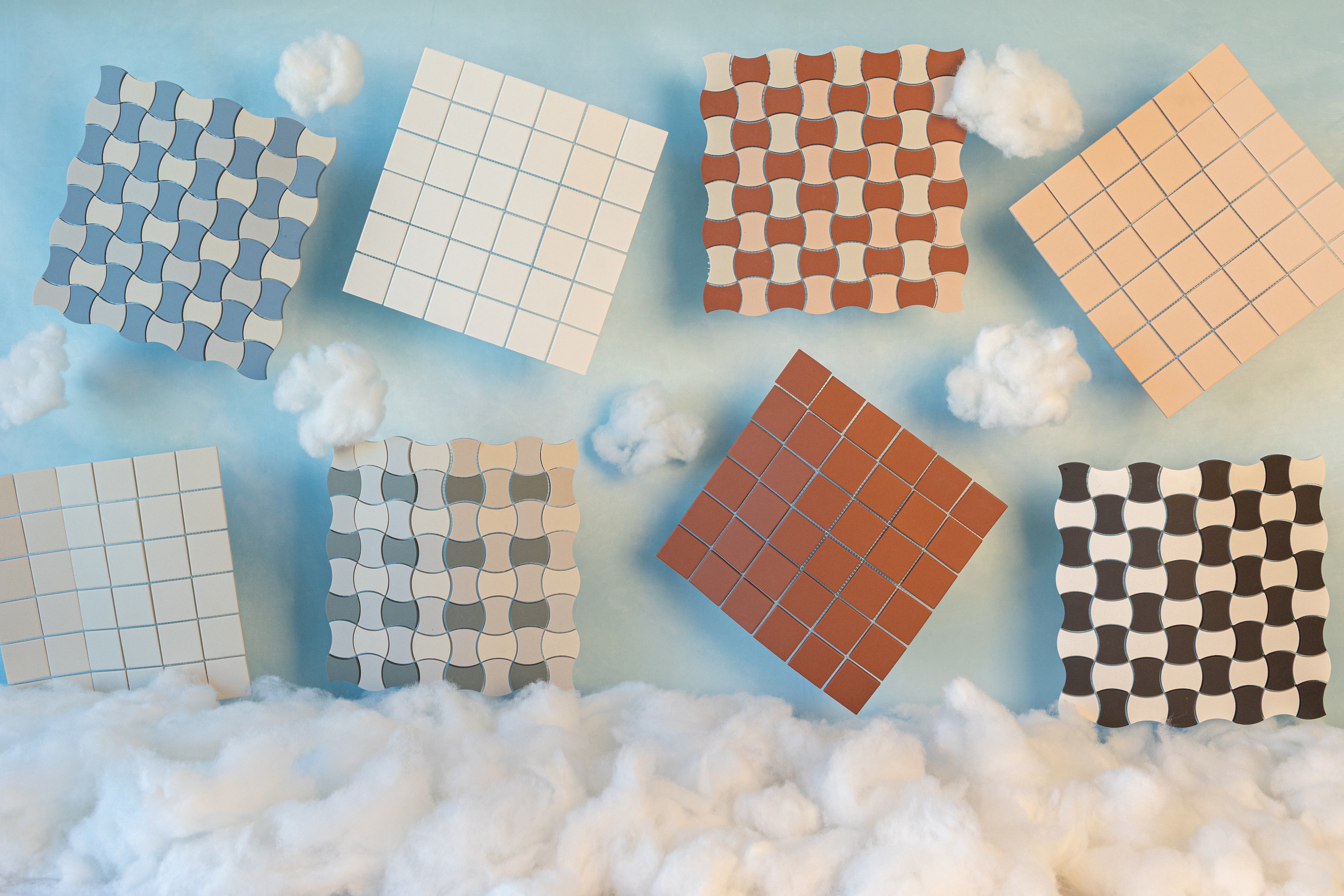 Eight floating ceramic tiles in varied blue, beige, and brown tones with grid and wave patterns above soft white clouds