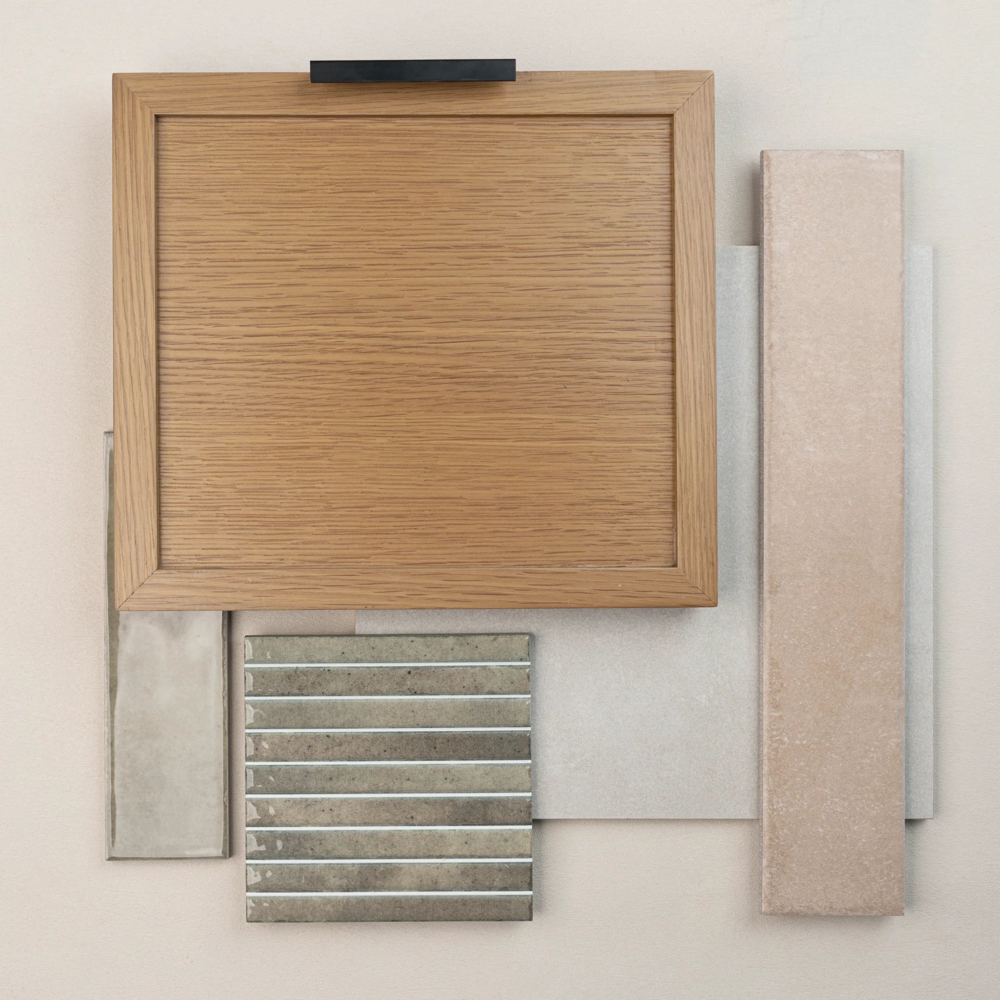 Wood sample with various beige and gray ceramic and porcelain tile swatches arranged on a neutral background