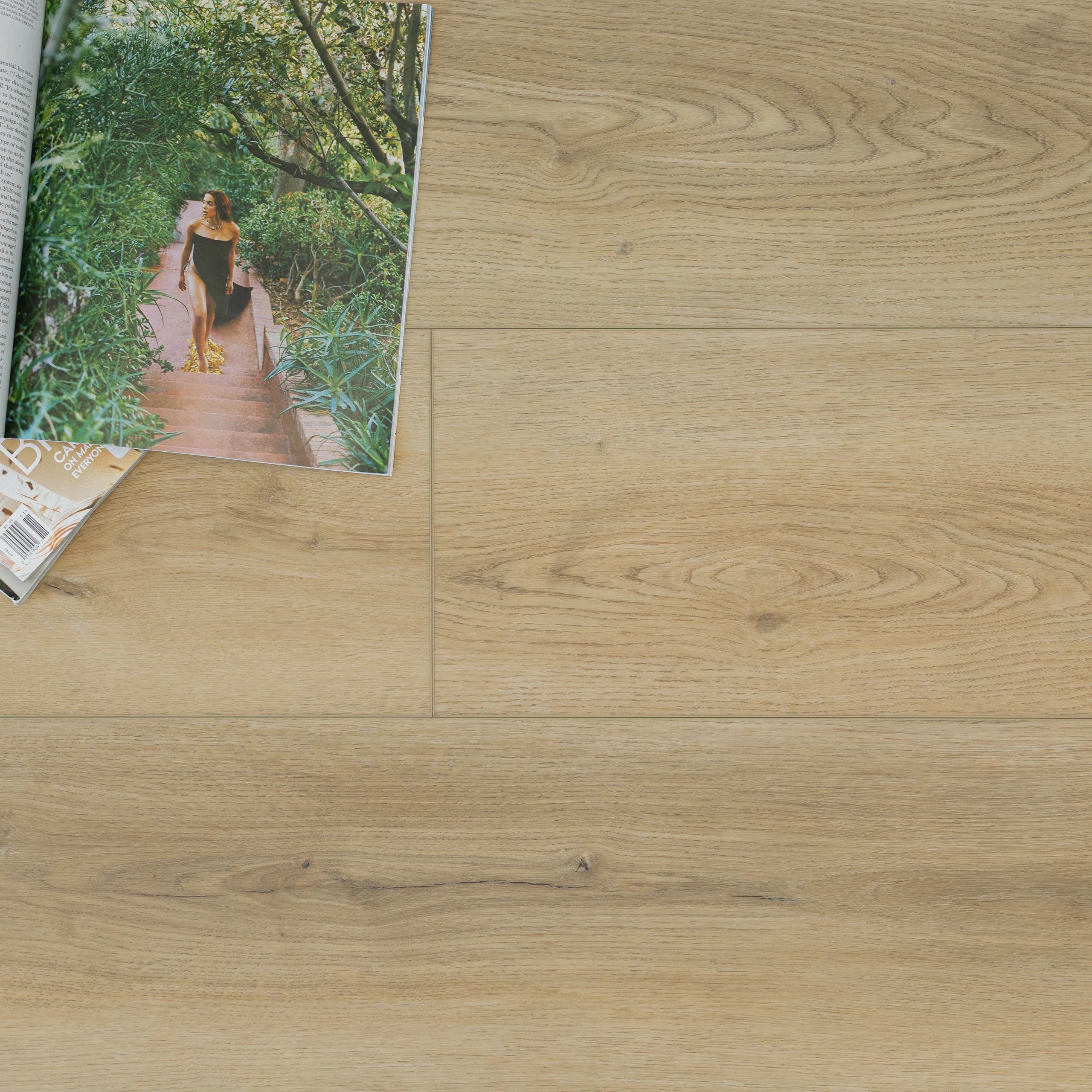 Light natural oak vinyl flooring with subtle grain patterns and a magazine resting on the surface