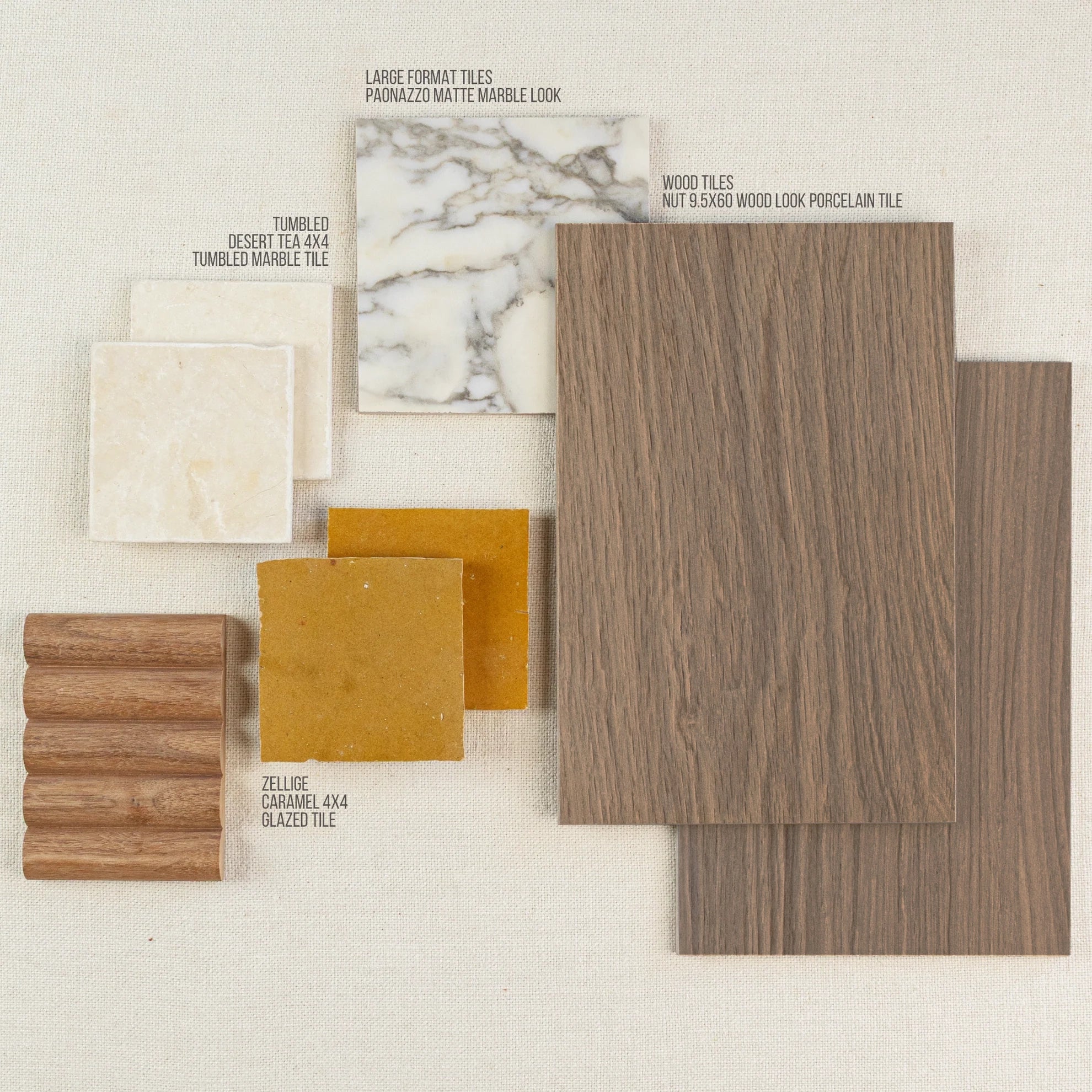 Assortment of wood-look porcelain, caramel glazed zellige, tumbled marble, and large format matte marble tiles on neutral fabric background