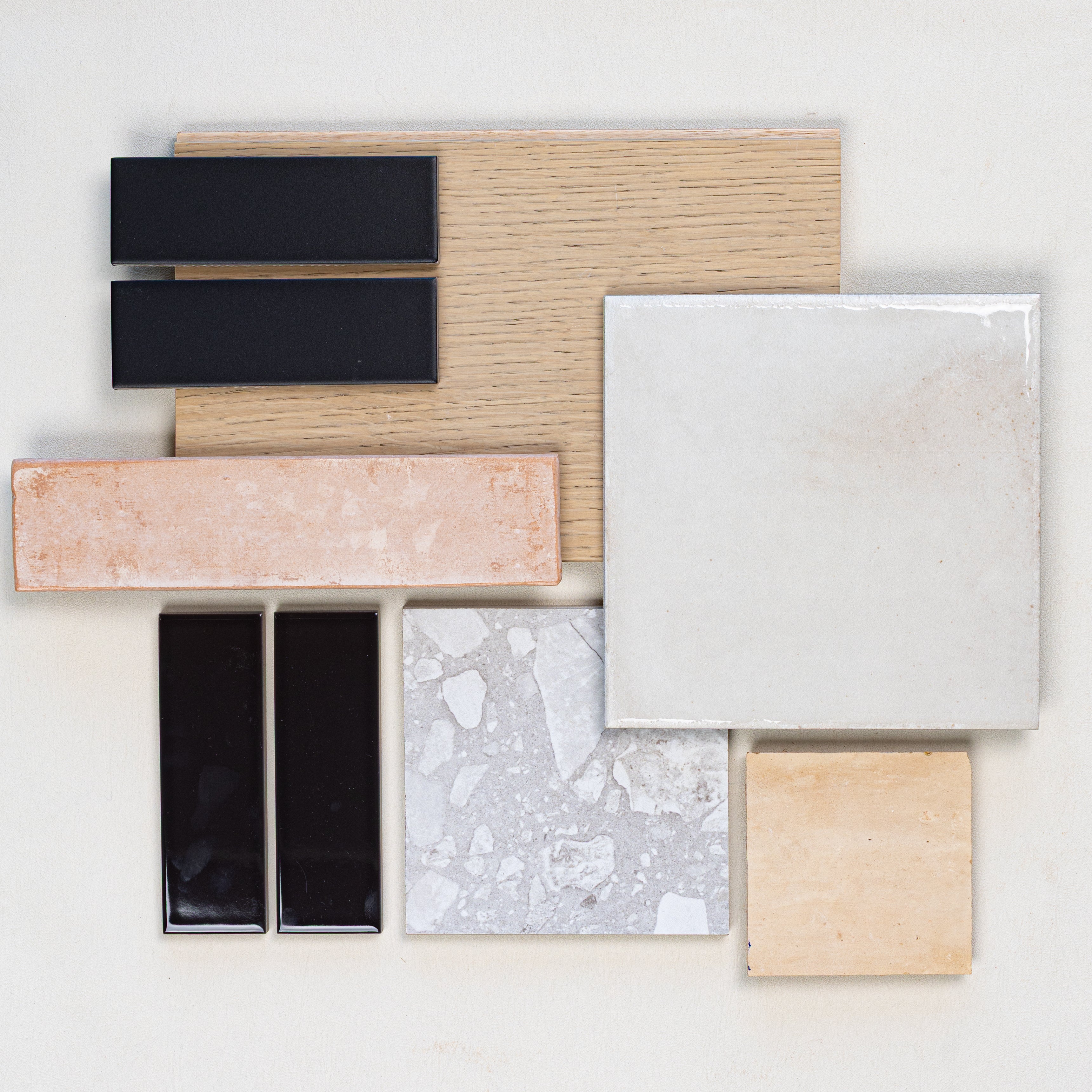 Assorted tile and flooring samples including ceramic, porcelain, engineered wood, and decorative tiles arranged on a white surface