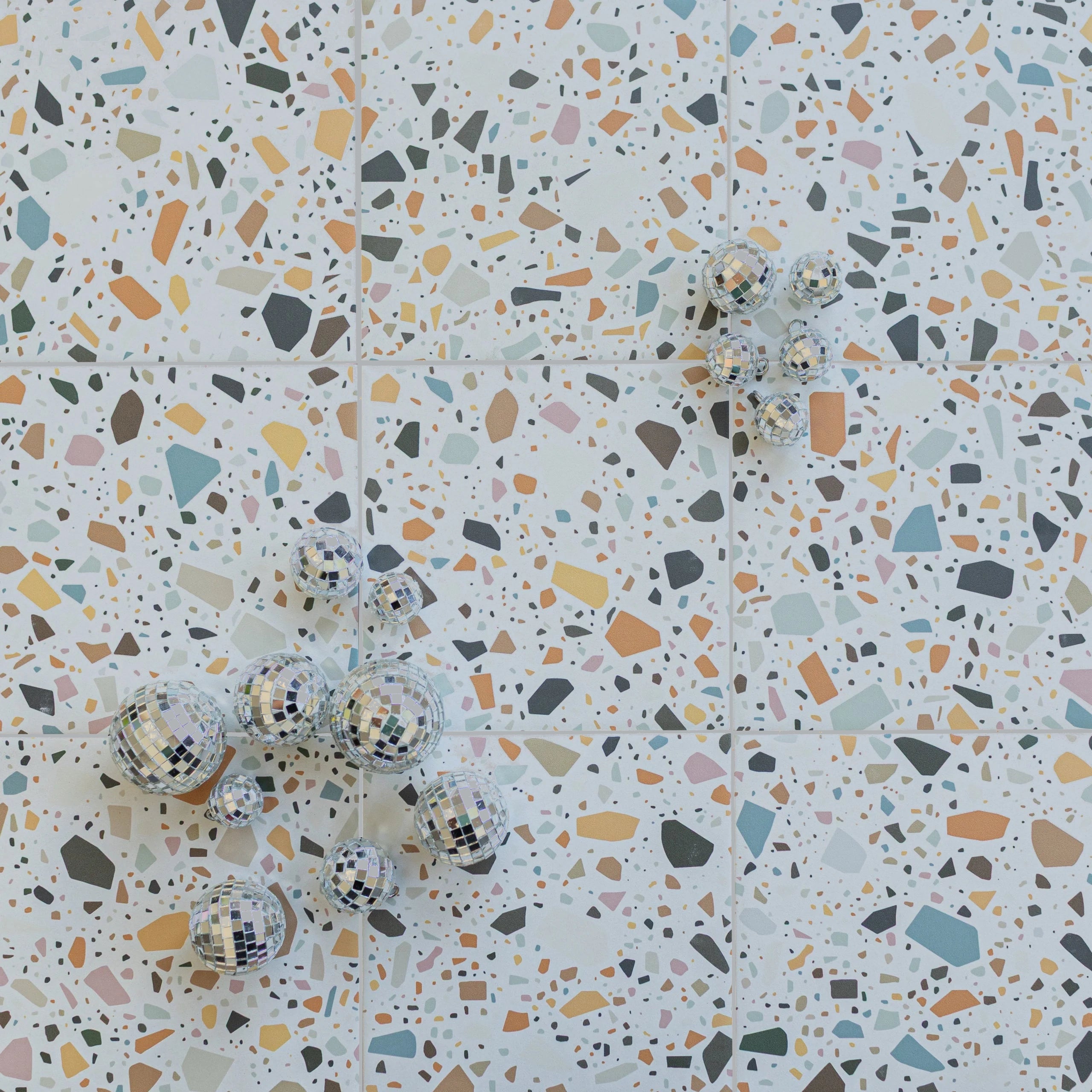 Close-up of matte porcelain tile with multicolored terrazzo pattern and small reflective mosaic spheres scattered on surface