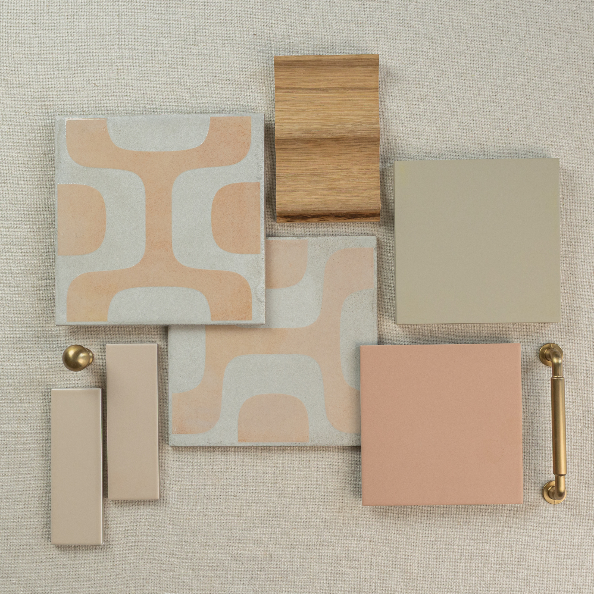 Flat layout of peach and beige ceramic tiles, light oak wood sample, brass hardware, and neutral fabric background