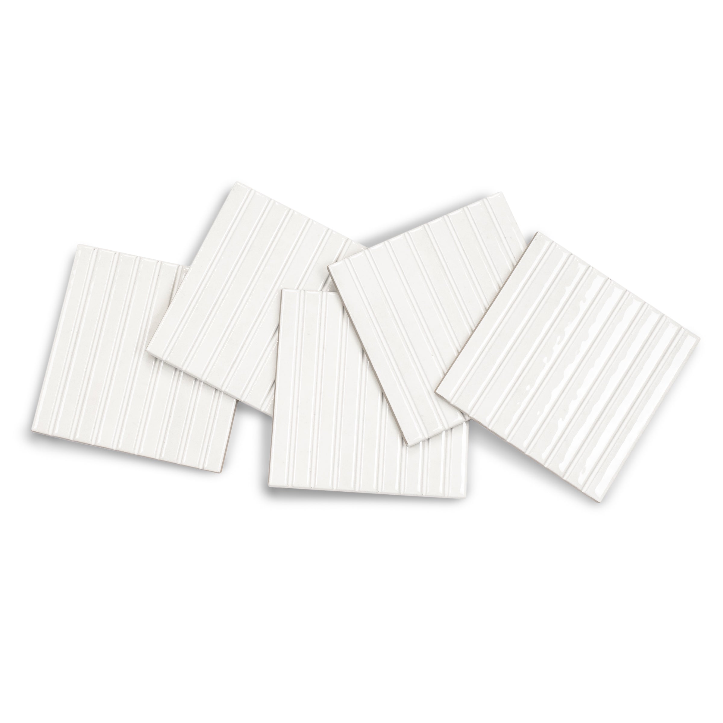 Five white square ceramic tiles with thin vertical grooves and a smooth matte finish arranged on a white surface
